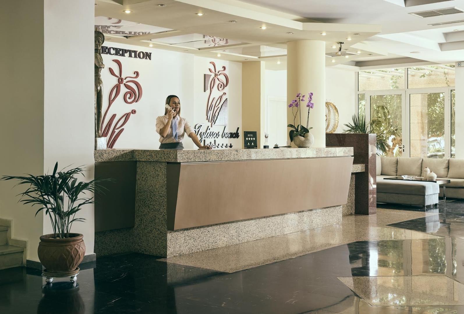 Tylissos Beach Hotel recepcijas lete ar darbinieci, gaišs vestibils ar marmora grīdu un dekoratīviem elementiem