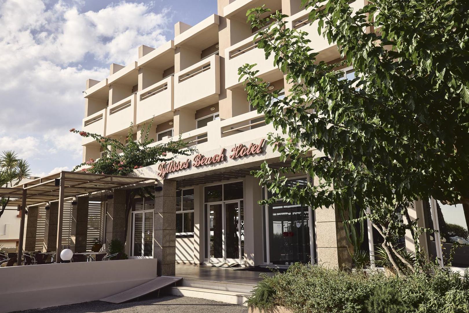 Tylissos Beach Hotel galvenā ieeja un numuri ar balkoniem dienas laikā — gaiša un moderna viesnīcas ēka Ierapetrā