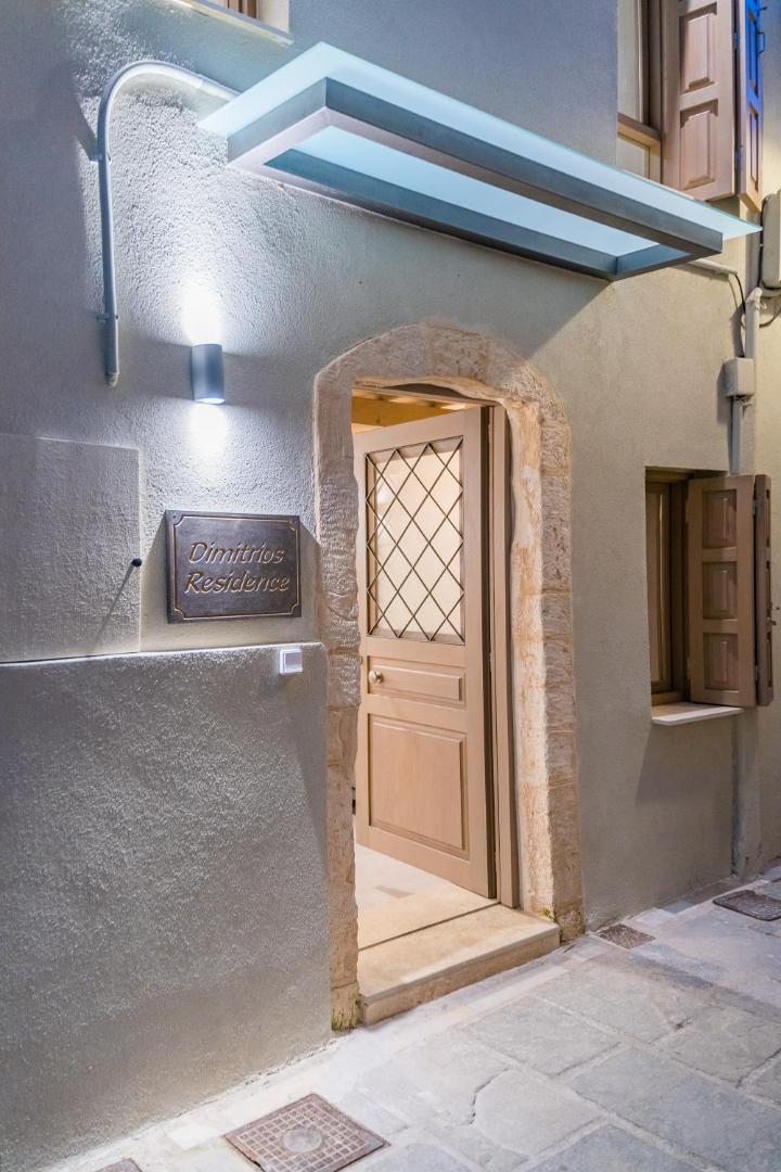 Tuvplāns Dimitrios Residence ieejas durvīm un nosaukuma plāksnei pie akmens mūra sienas Retimno.