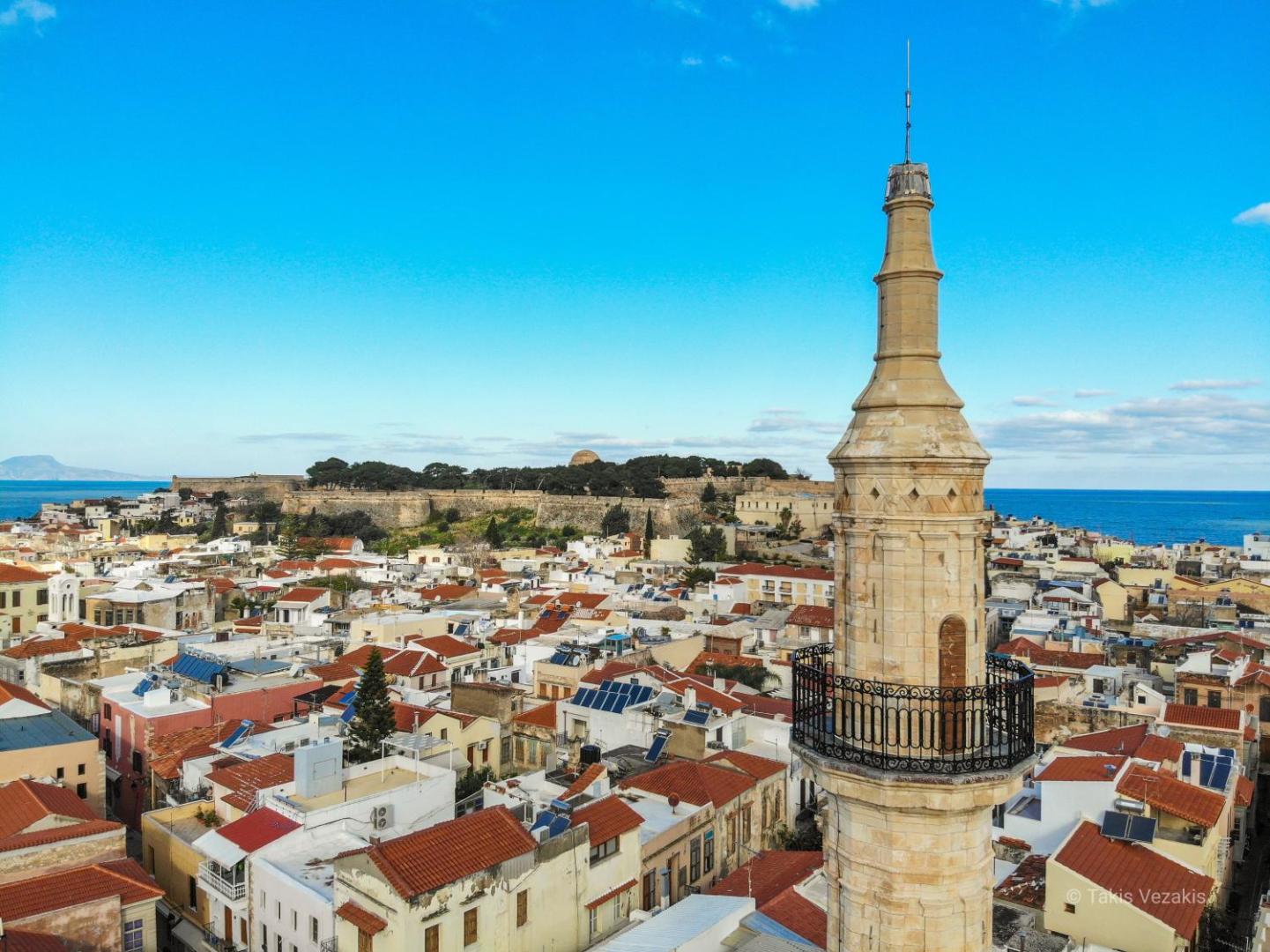 Skats uz Retimno vecpilsētas jumtiem un vēsturisko minaretu netālu no Dimitrios Beach viesnīcas, fonā redzams Fortezza cietoksnis