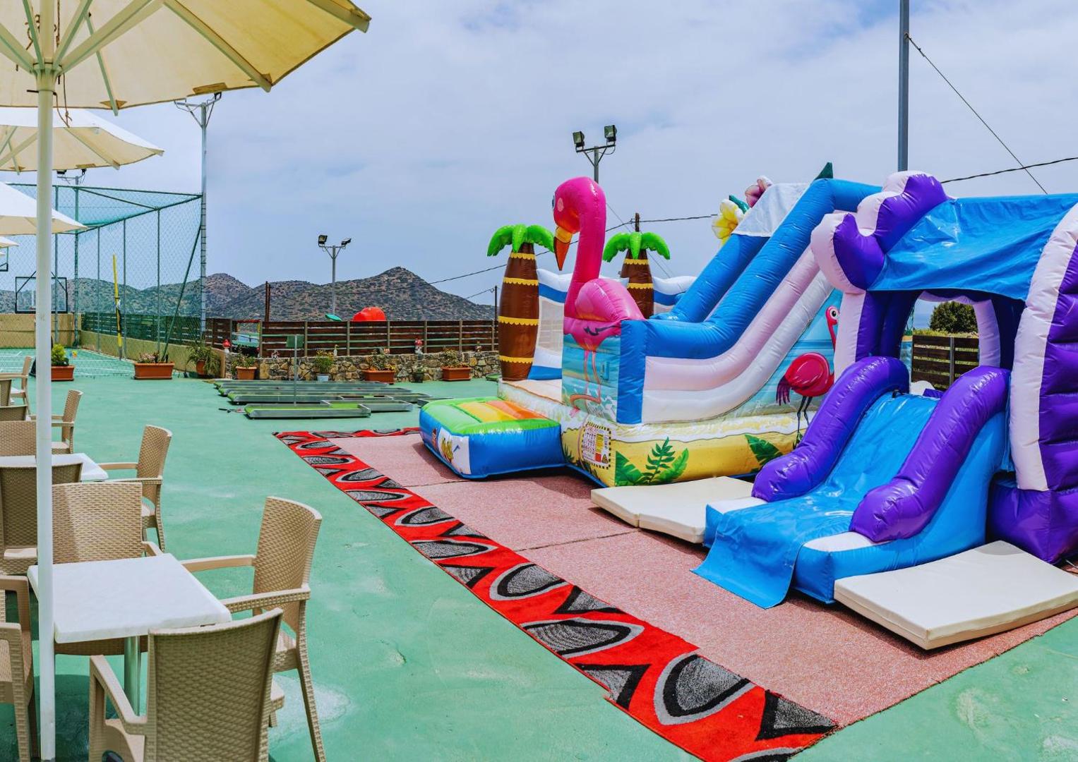 Elounda Waterpark Residence Hotel bērnu rotaļu laukums ar piepūšamajām atrakcijām, slidkalniņiem un galda spēlēm āra terasē