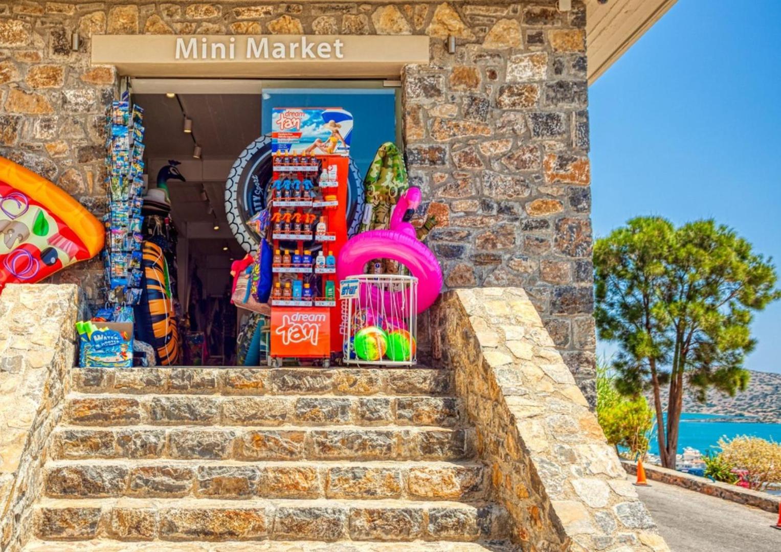 Elounda Waterpark Residence Hotel mini mārkets ar pludmales piederumiem un suvenīriem — akmens ēka ar skatu uz jūru Eloundā