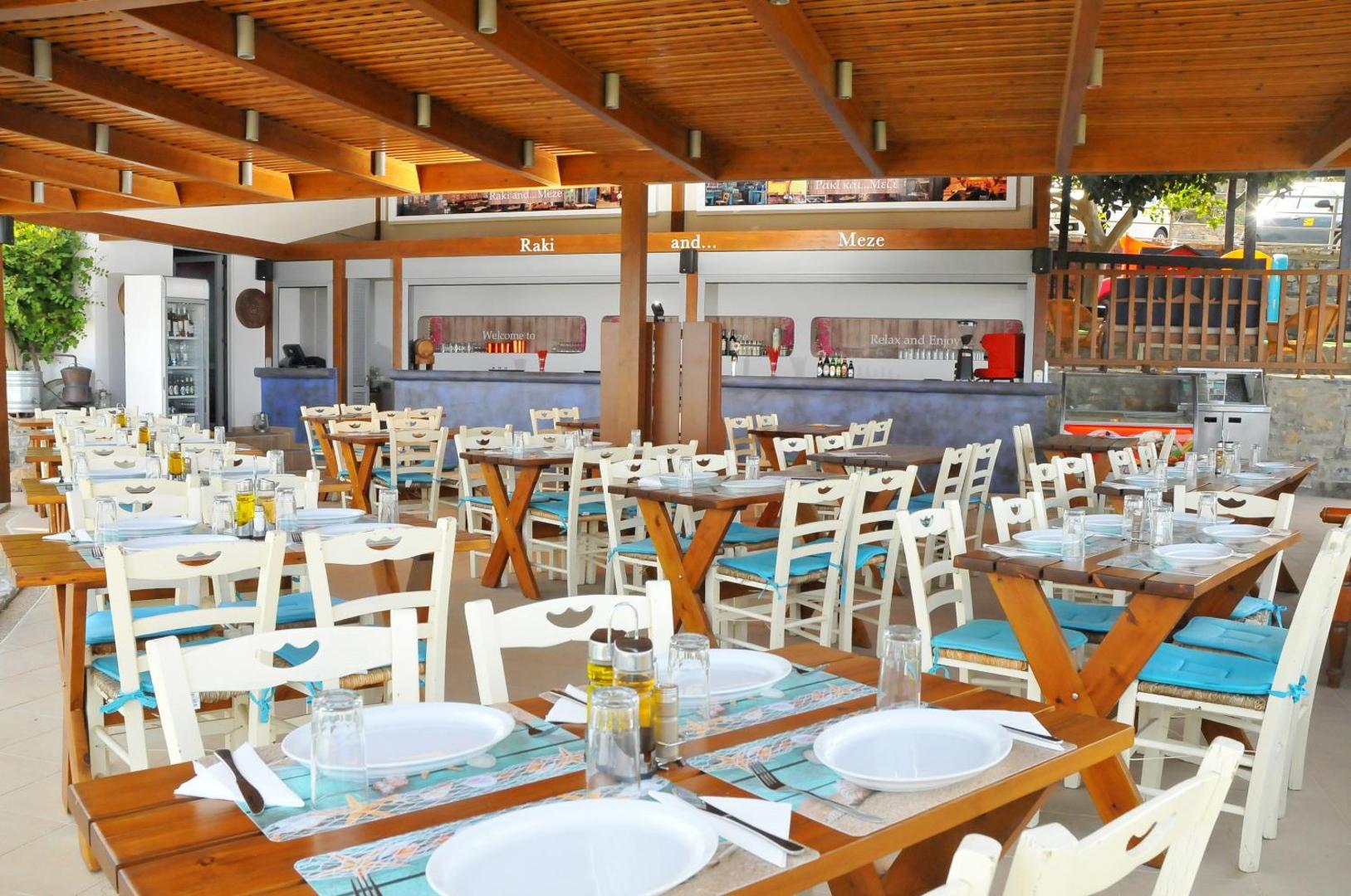 Elounda Waterpark Residence Hotel restorāns ar koka nojumi un tradicionālu grieķu stila iekārtojumu