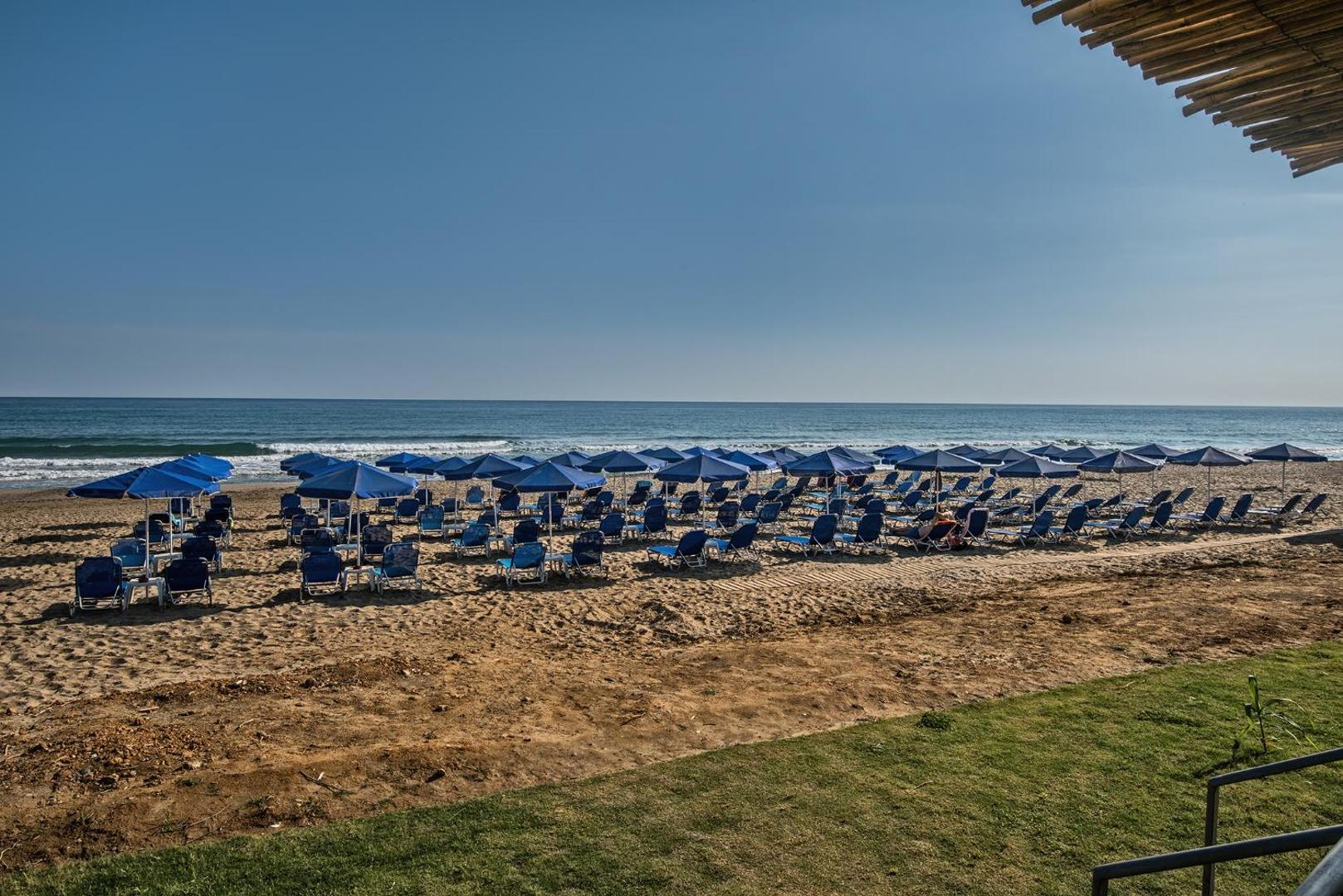 Skats uz Happy Days Beach pludmales zonu ar daudziem saulessargiem un tiešu pieeju dzidrajam Vidusjūras ūdenim Krētas salā.