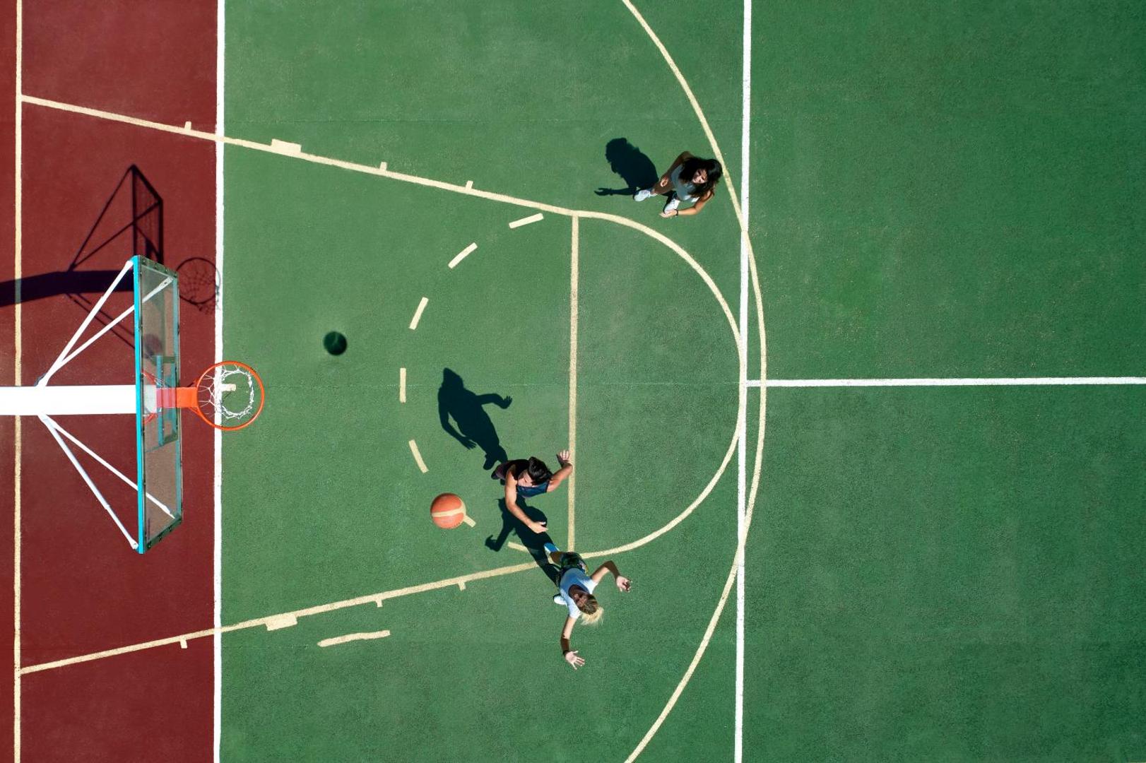 Lindos Princess Beach Hotel basketbola laukums no putna lidojuma Rodas salā — viesi spēlē basketbolu uz zaļa un sarkana seguma