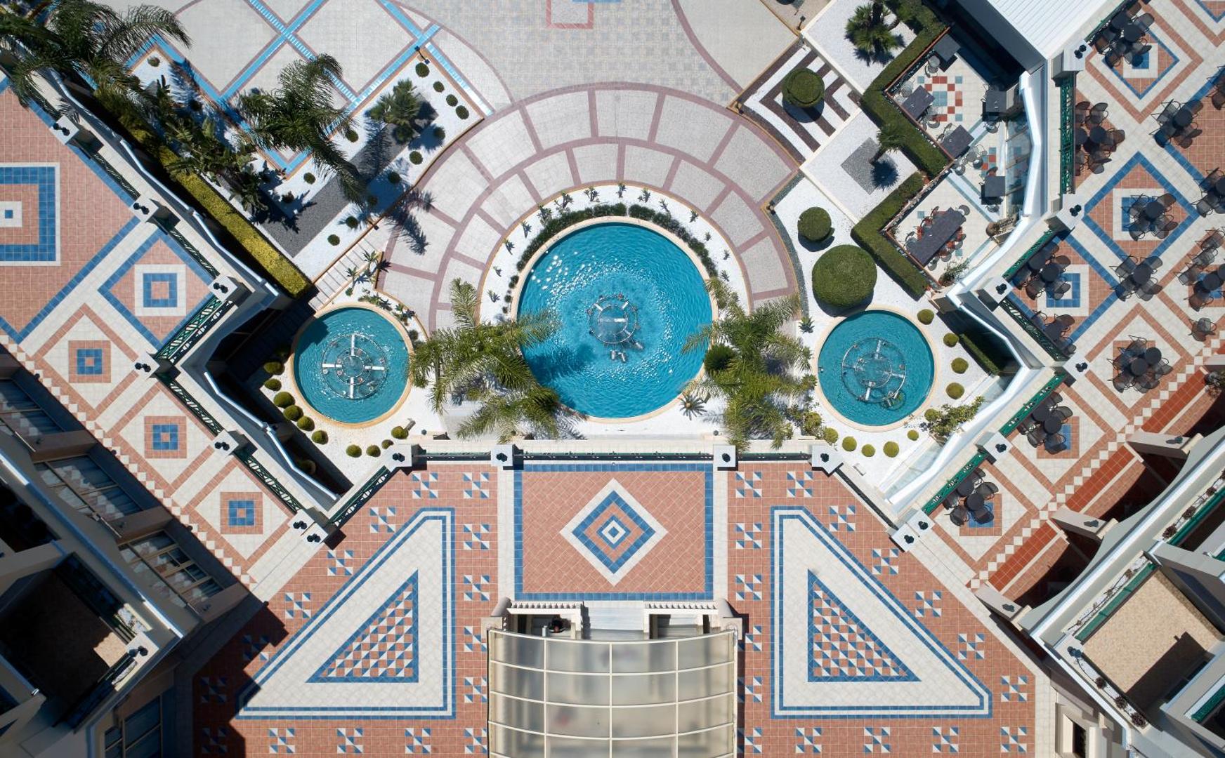 Lindos Princess Beach Hotel centrālā laukuma rakstainais flīžu klājums un dekoratīvie strūklaku baseini ar palmām Rodas salā.