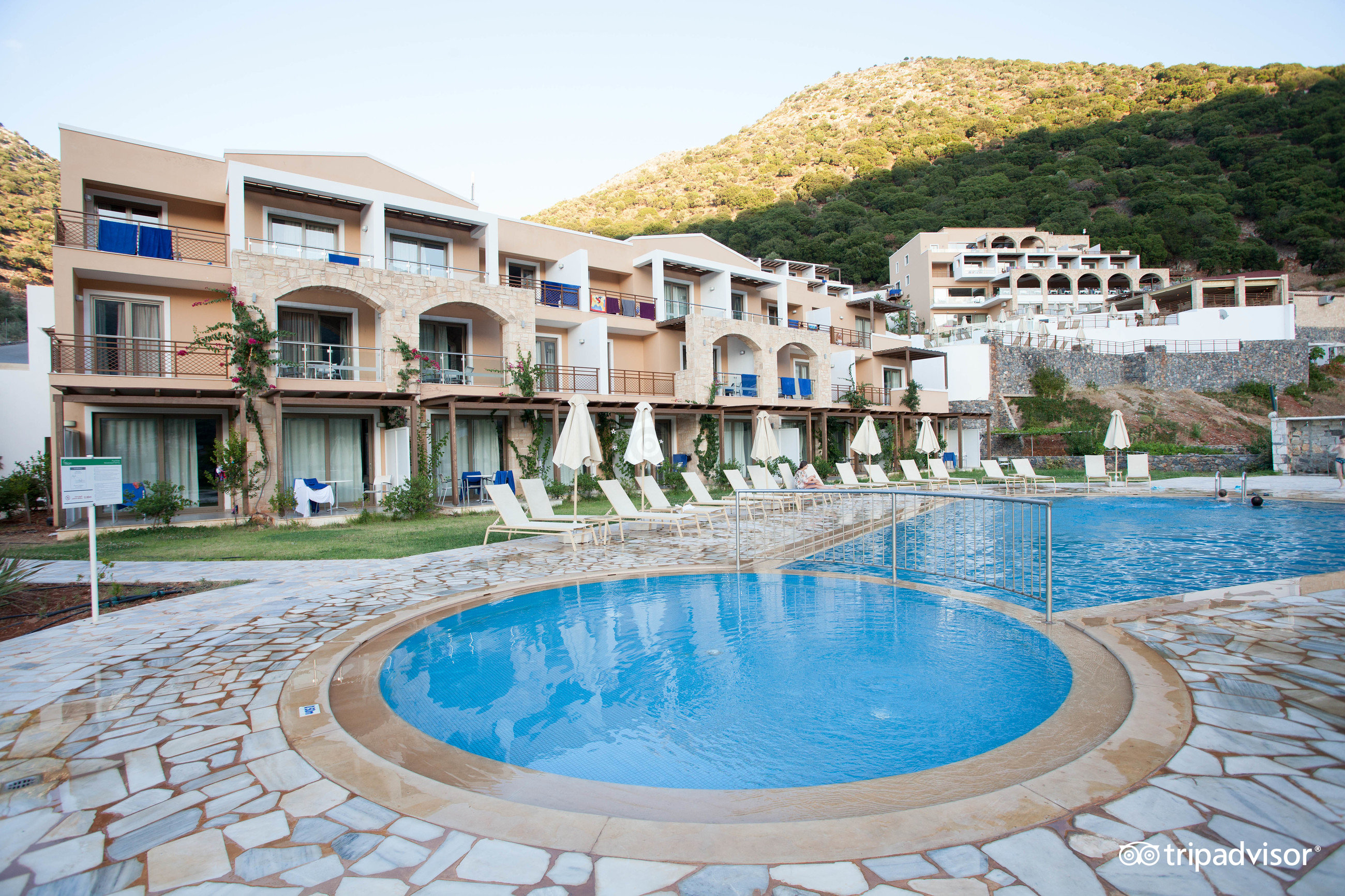Filion Suites Resort & Spa galvenais baseins un viesnīcas korpusi Bali ciematā, Krētā — saulaina terase ar zviļņiem un kalnu ainavu