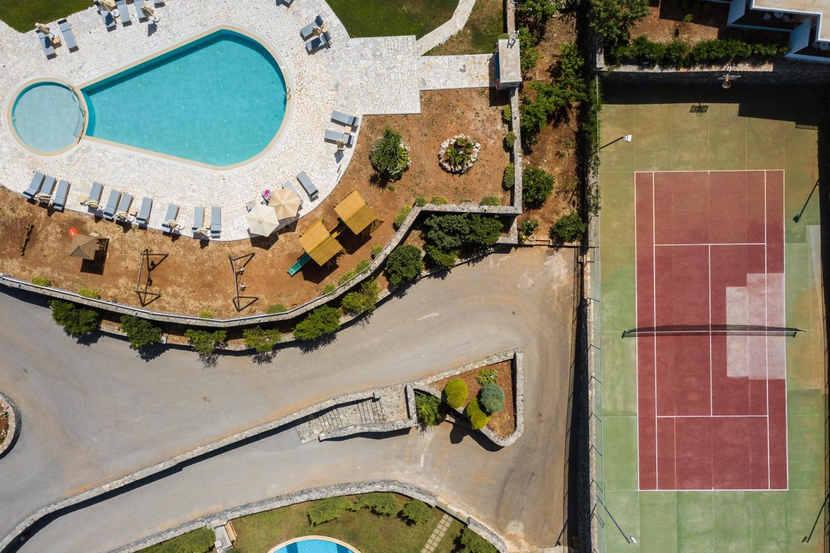 Filion Suites Resort & Spa teritorijas skats no putna lidojuma Bali, Krētā — redzams āra baseins, tenisa korts un bērnu rotaļu laukums