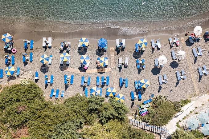 Filion Suites Resort & Spa privātā pludmale Bali, Krētā — skats no augšas uz krāsainiem saulessargiem un zviļņiem smiltīs