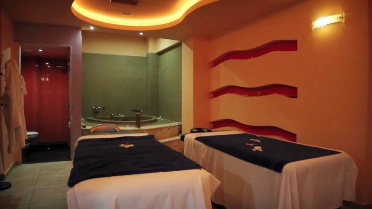 Filion Suites Resort & Spa spa centrs ar divām masāžas gultām un džakuzi vannu fonā mājīgā apgaismojumā