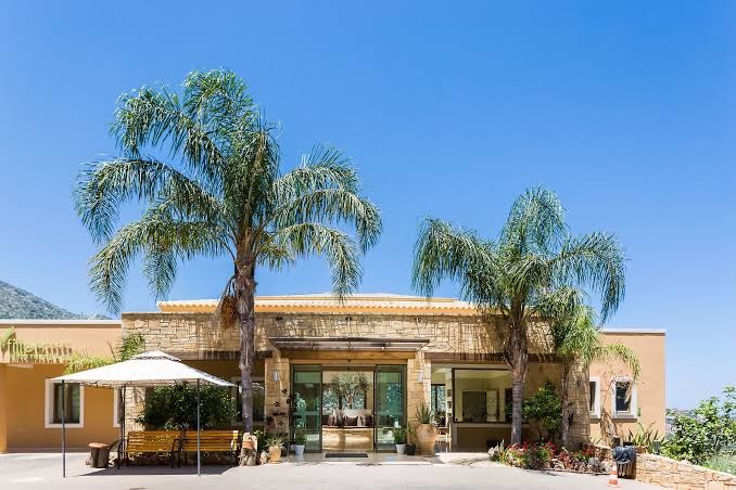 Filion Suites Resort & Spa galvenā ieeja un vestibila ēka ar akmens apdari, palmām un atpūtas zonu zem saulessarga