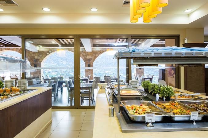 Filion Suites Resort & Spa galvenais restorāns ar bagātīgu bufetes izvēli un skatu caur lielajiem logiem uz Krētas kalniem