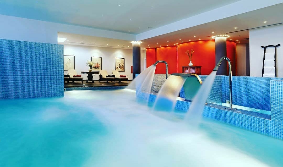 Out Of The Blue Resort & Spa spa centrs ar iekštelpu baseinu un ūdens kaskādēm — zilu mozaīkas flīžu apdare un atpūtas krēsli