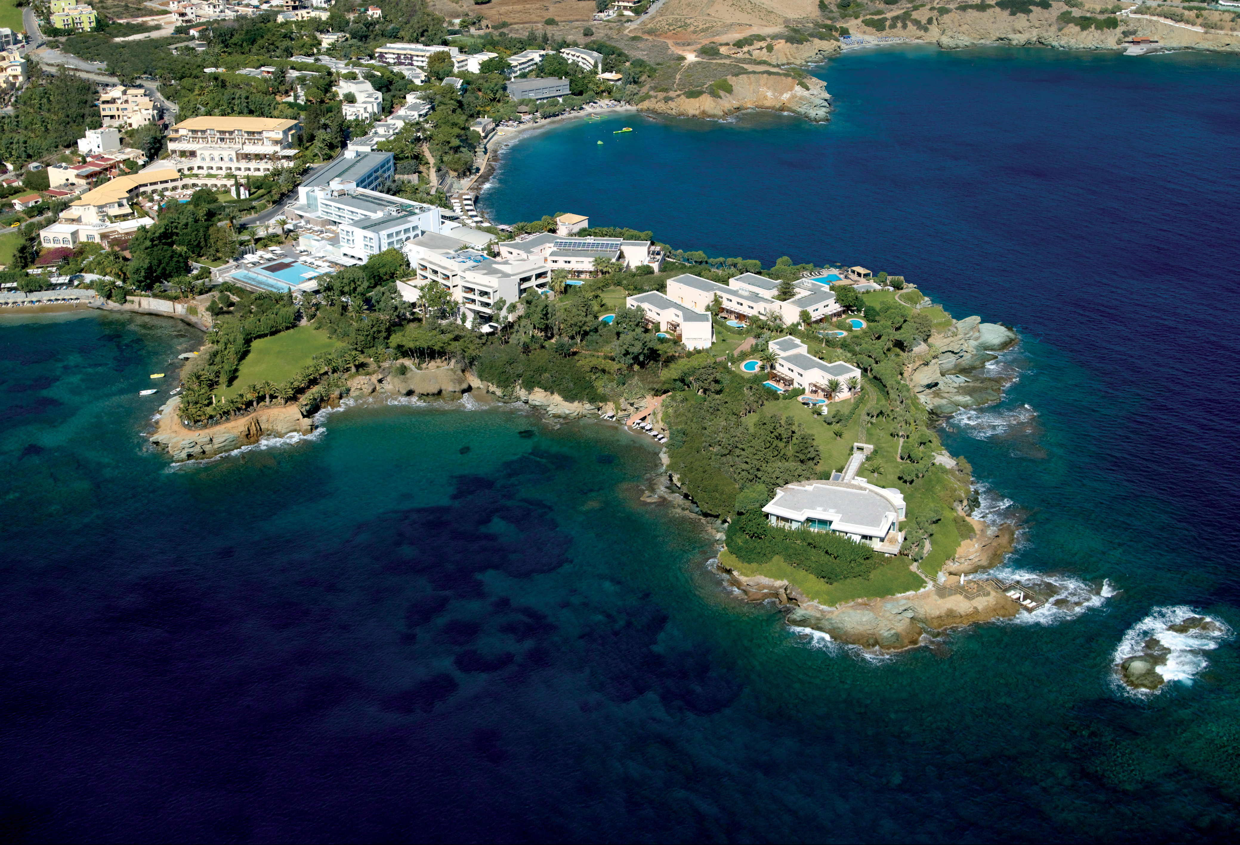 Out Of The Blue Resort & Spa panorāmas skats no putna lidojuma uz Agia Pelagia pussalu Krētā ar viesnīcas ēkām un līčiem