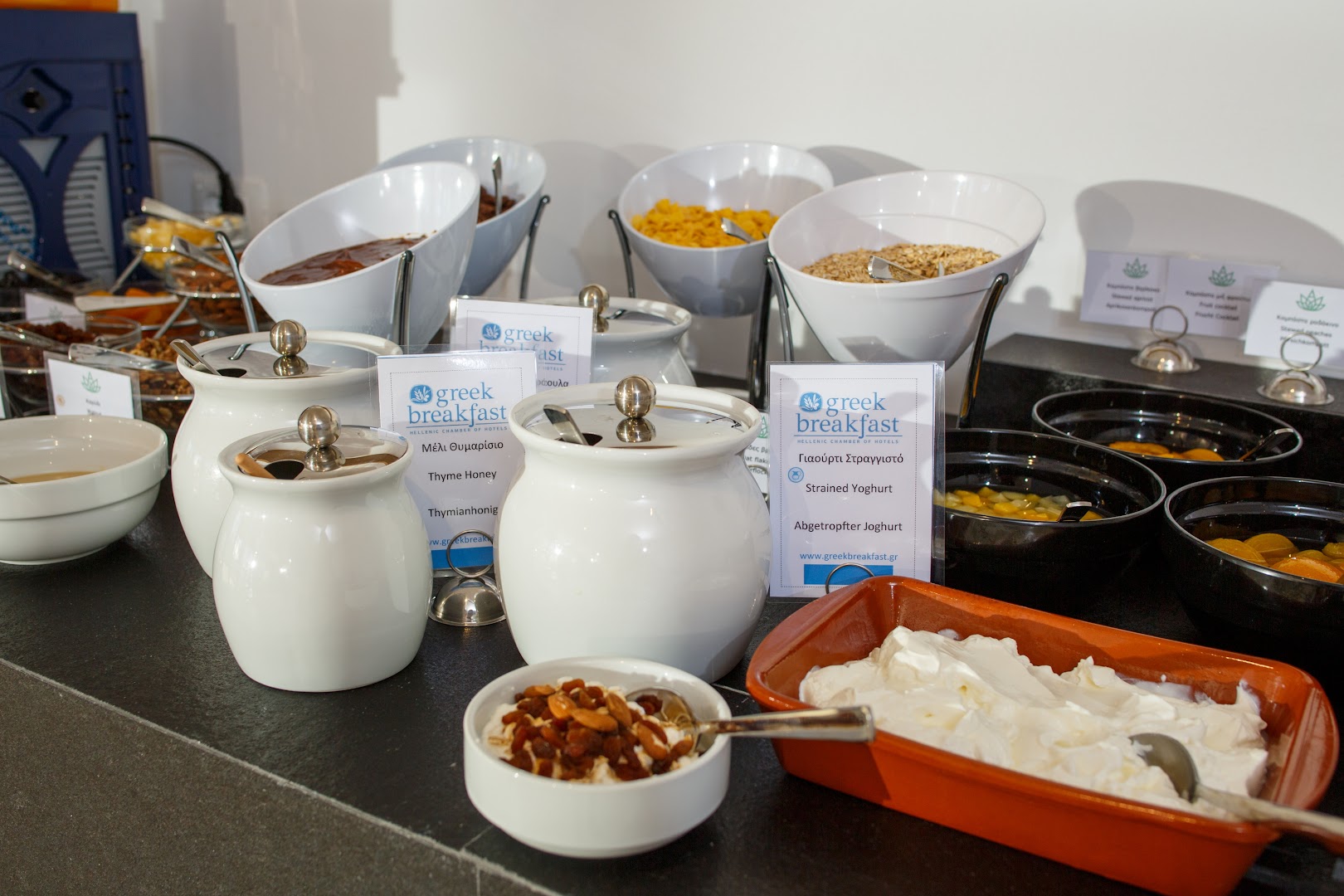 Tradicionālo grieķu brokastu produkti Aloe Boutique Hotel, tostarp jogurts, medus un rieksti, glīti pasniegti traukos