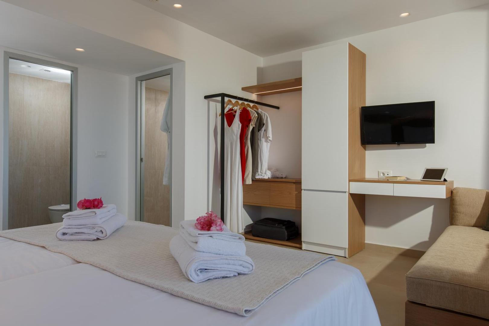 Aloe Boutique Hotel moderns numura interjers ar divguļamo gultu, drēbju pakaramo, darba zonu un ieeju vannas istabā.