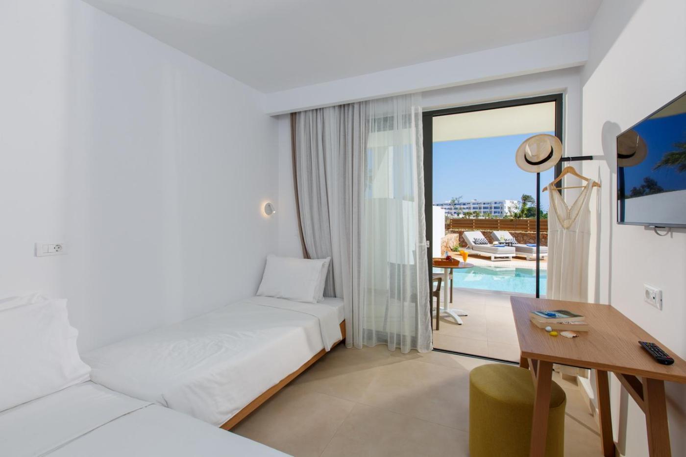 Aloe Boutique Hotel numurs ar tiešu piekļuvi baseinam, gaišs interjers ar divām gultām un terasi, kurā atrodas sauļošanās krēsli.