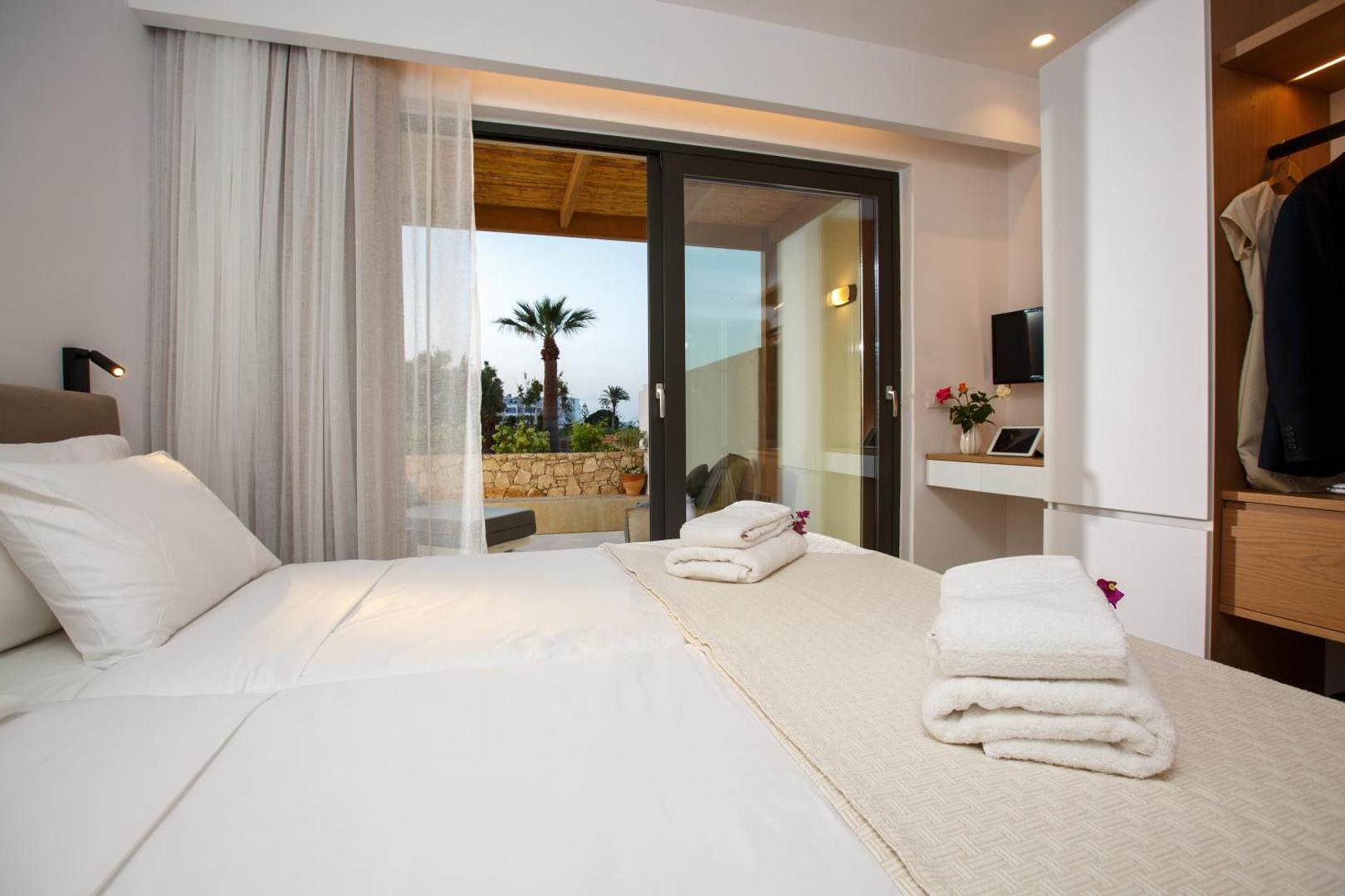 Aloe Boutique Hotel numura skats no gultas uz terasi un palmu, gaiši aizkari un elegants interjers Hersonisā.