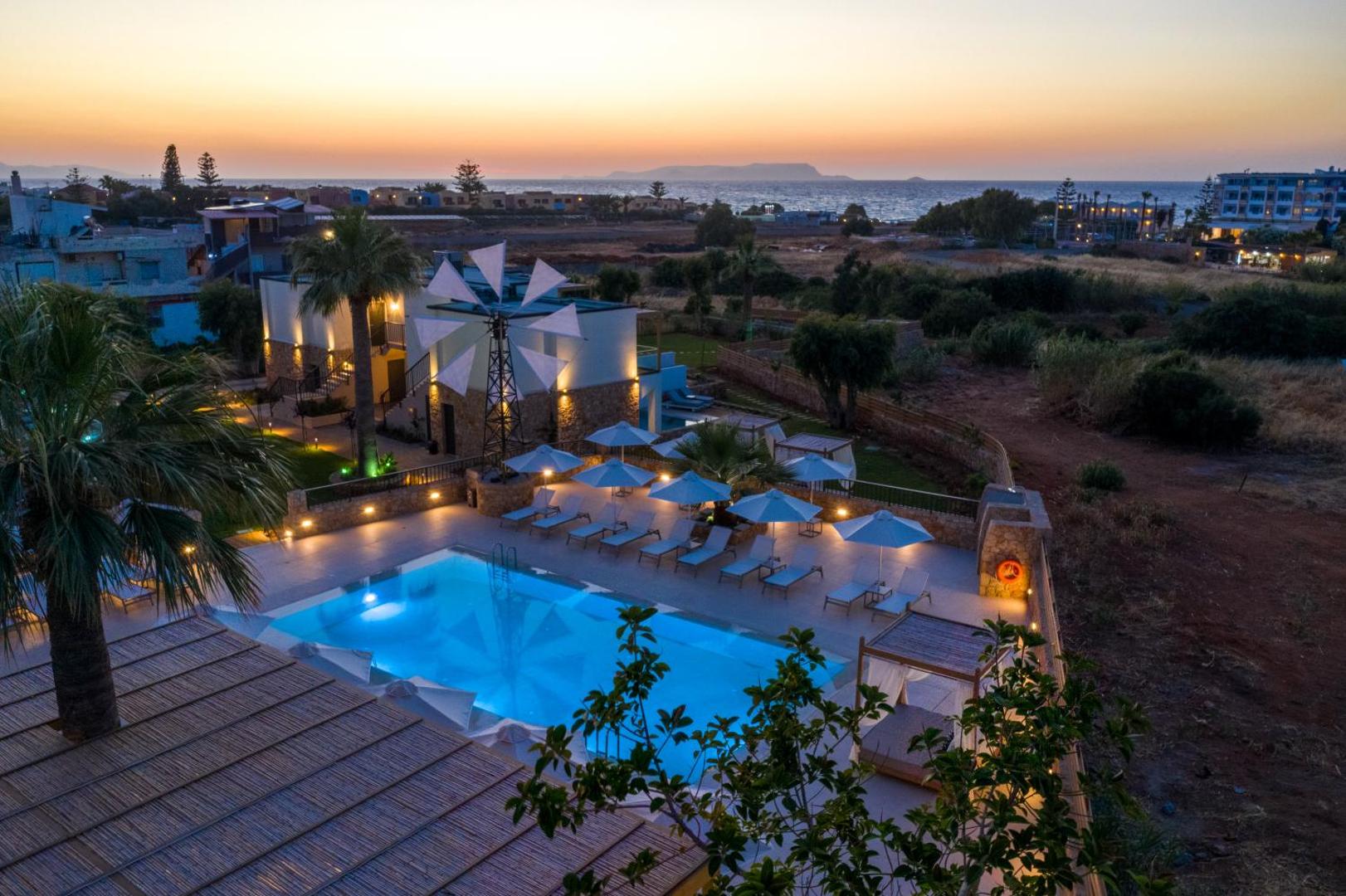 Aloe Boutique Hotel panorāmas skats no augšas uz baseinu, viesnīcas ēku un jūru saulrieta laikā Anisaras kūrortā