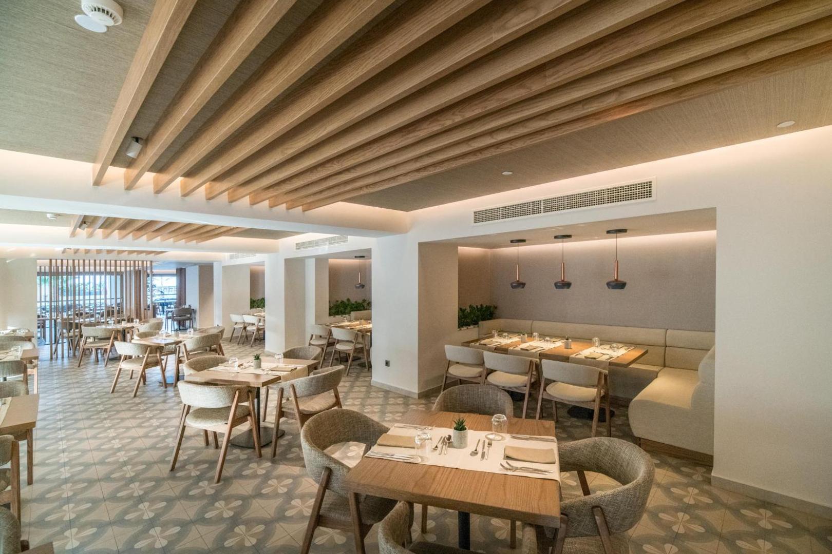 Akasha Beach Hotel & Spa iekštelpu restorāns ar modernu dizainu, koka griestu elementiem un mīkstiem krēsliem siltos toņos