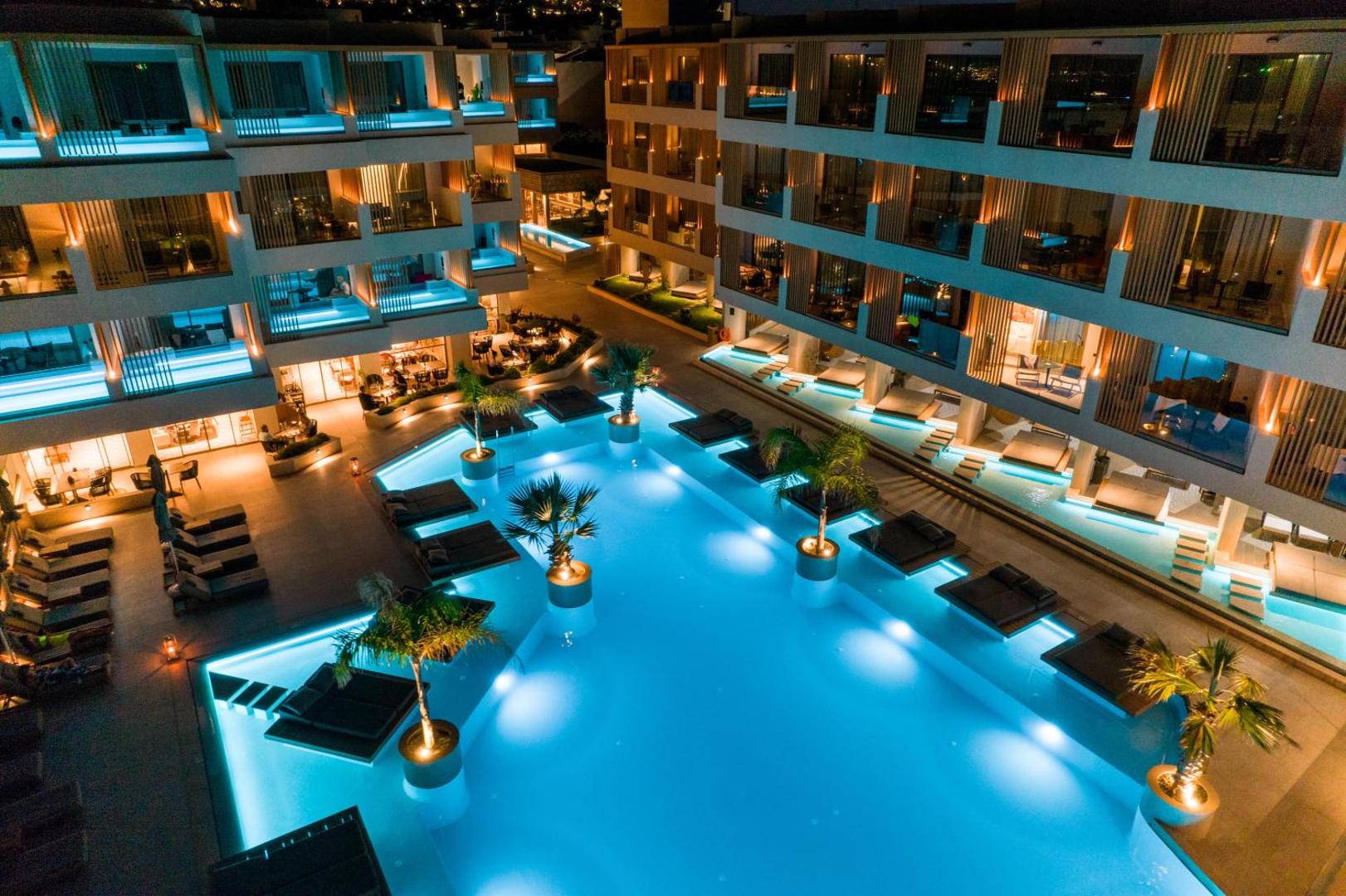 Akasha Beach Hotel & Spa vakara skats no augšas uz izgaismotu baseinu, palmām un viesnīcas fasādi Hersonisā