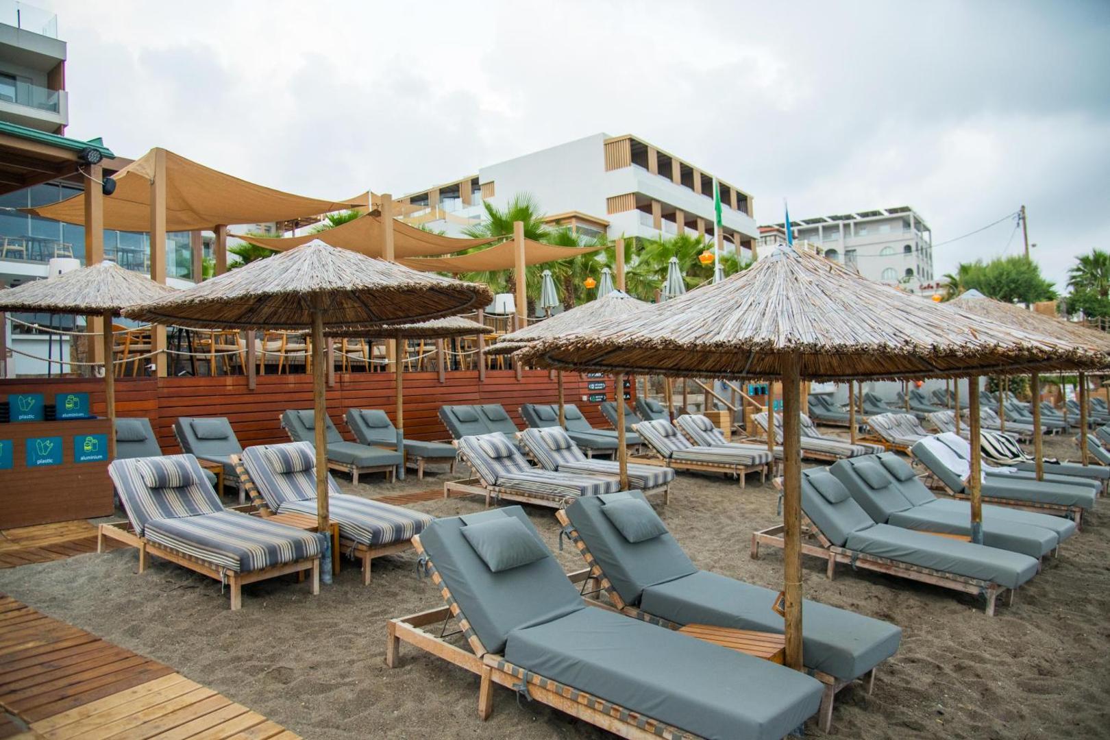 Akasha Beach Hotel & Spa privātā pludmale ar pelēkiem zviļņiem un salmu saulessargiem Hersonisas piekrastē, Krētā