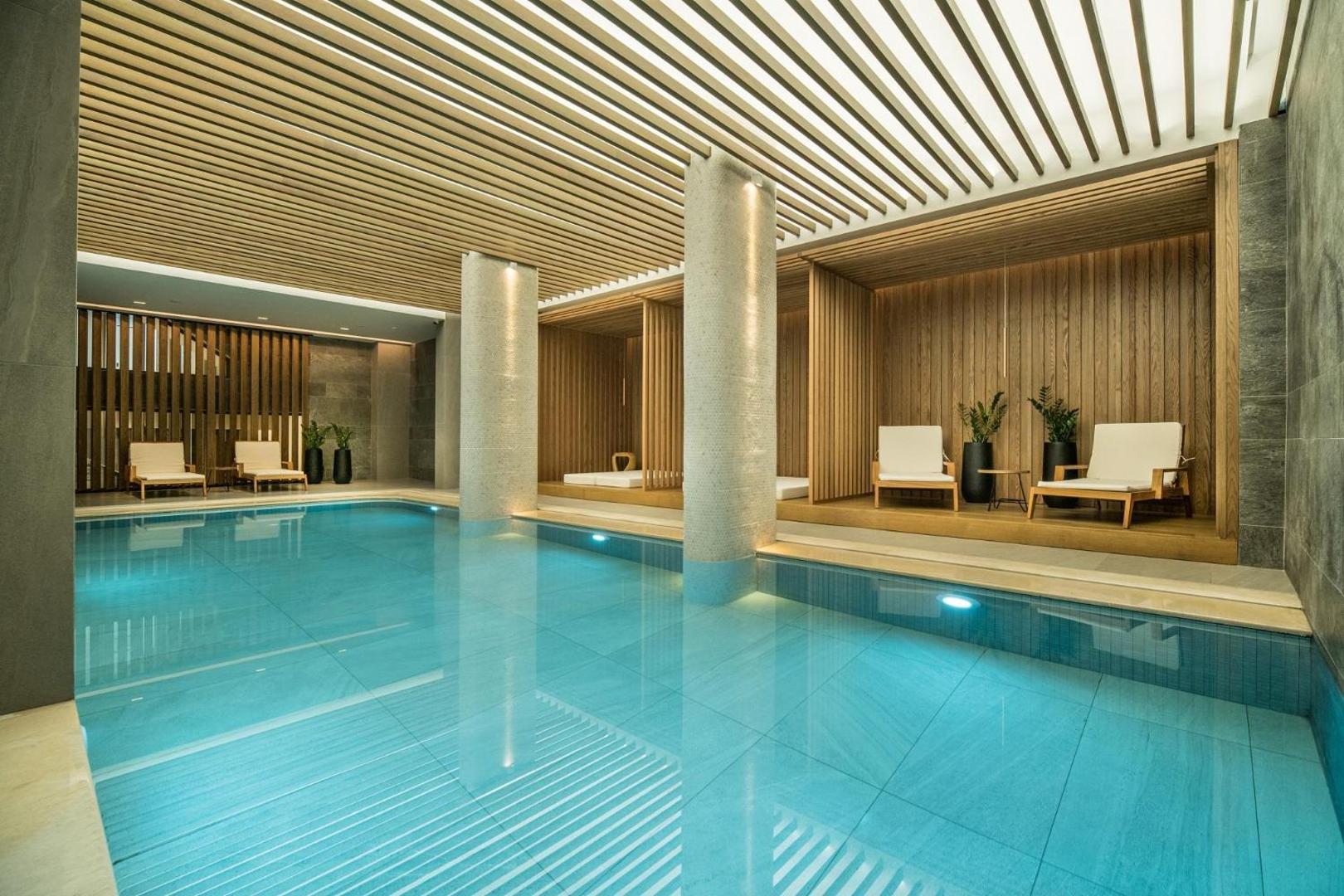Akasha Beach Hotel & Spa iekštelpu baseins ar koka apdares elementiem un ērtiem zviļņiem relaksācijas zonā