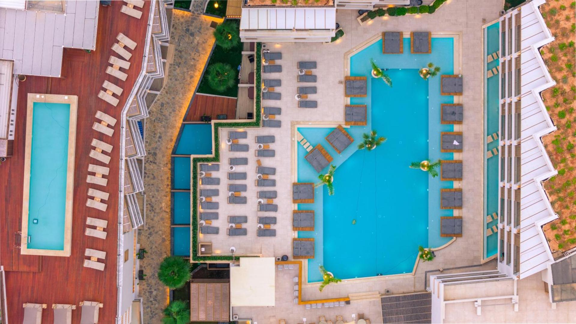 Akasha Beach Hotel & Spa skats no putna lidojuma uz galveno baseinu Hersonisā, Krētā — moderni sauļošanās krēsli un atpūtas zonas