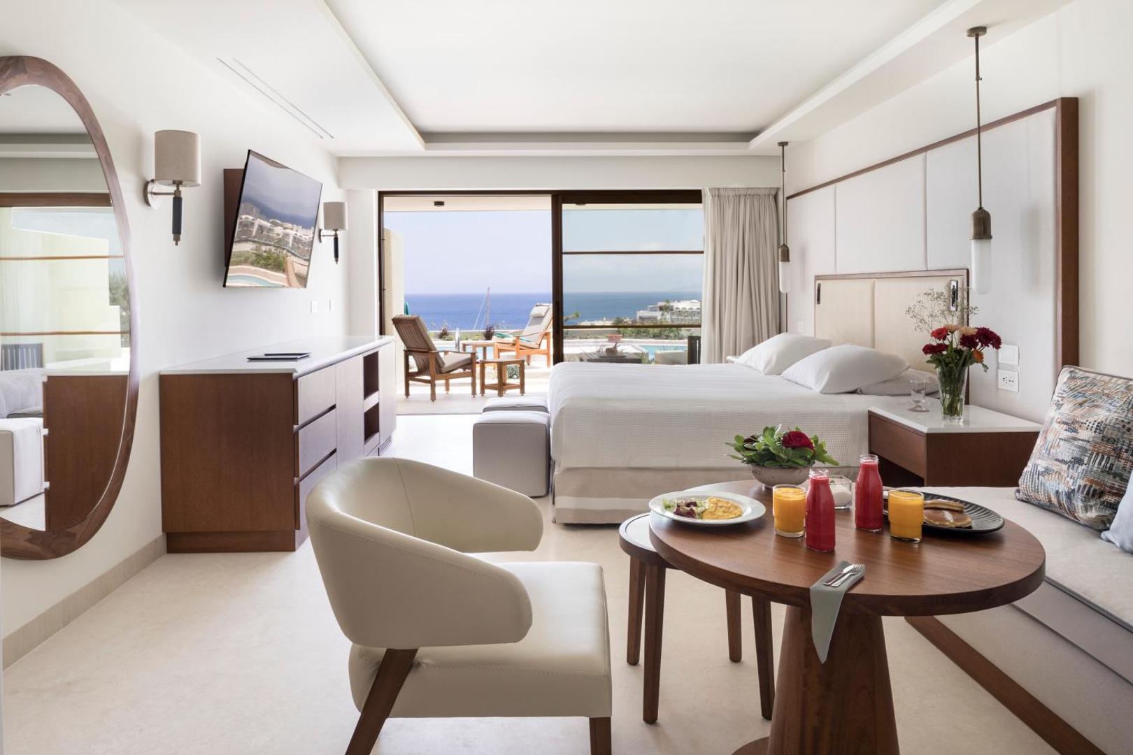 Porto Elounda Golf & Spa Resort gaišs numurs ar skatu uz jūru, balkonu un brokastu galdu priekšplānā