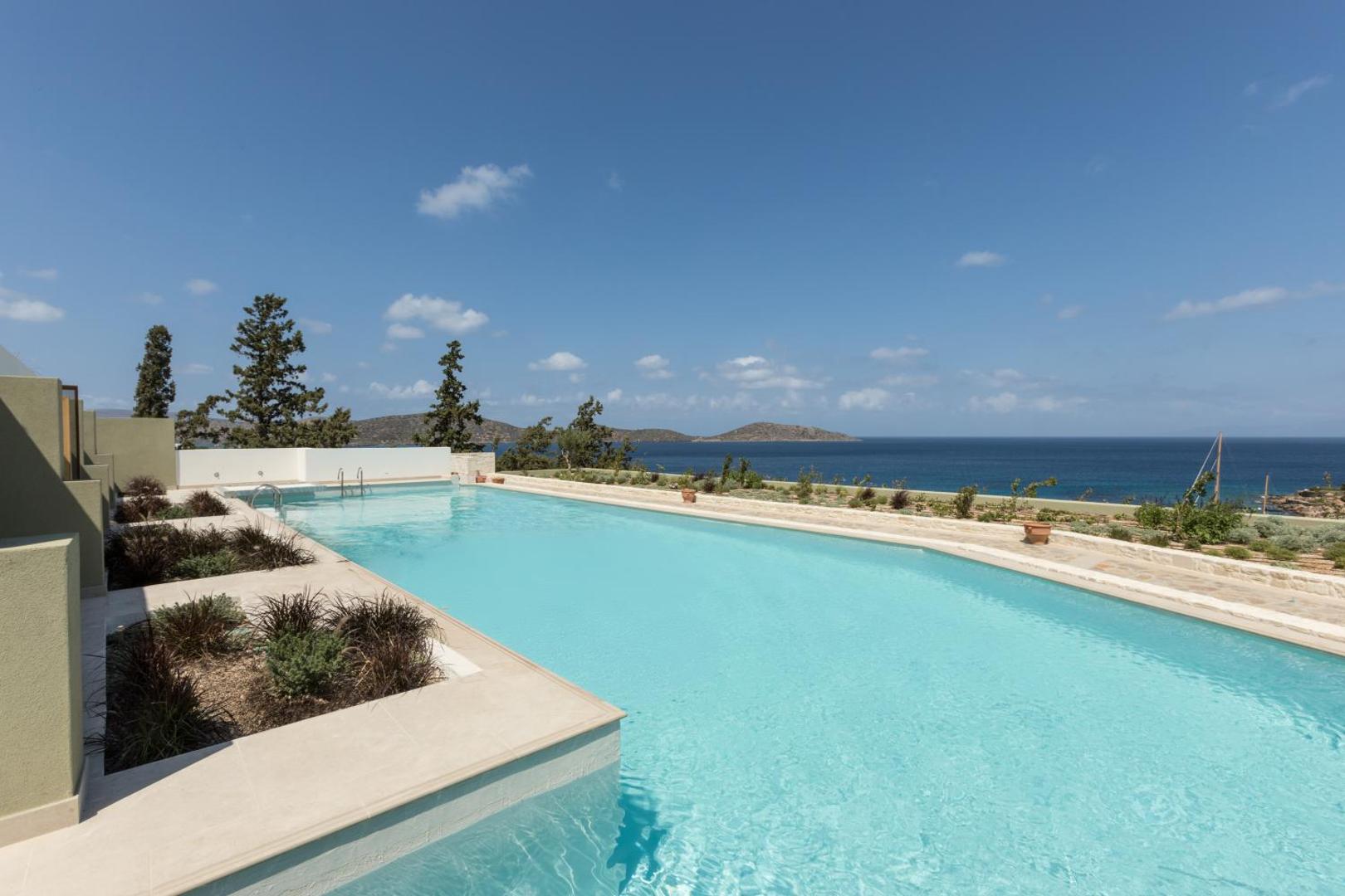 Porto Elounda Golf & Spa Resort āra baseins ar skatu uz jūru un kalniem Elundā, Krētas ziemeļu piekrastē