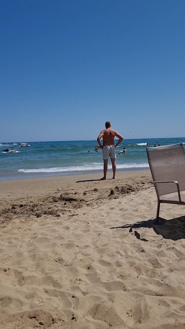 Skats no Kriti Beach Hotel pludmales uz zilo jūru un atpūtniekiem saulainā dienā Krētas salā
