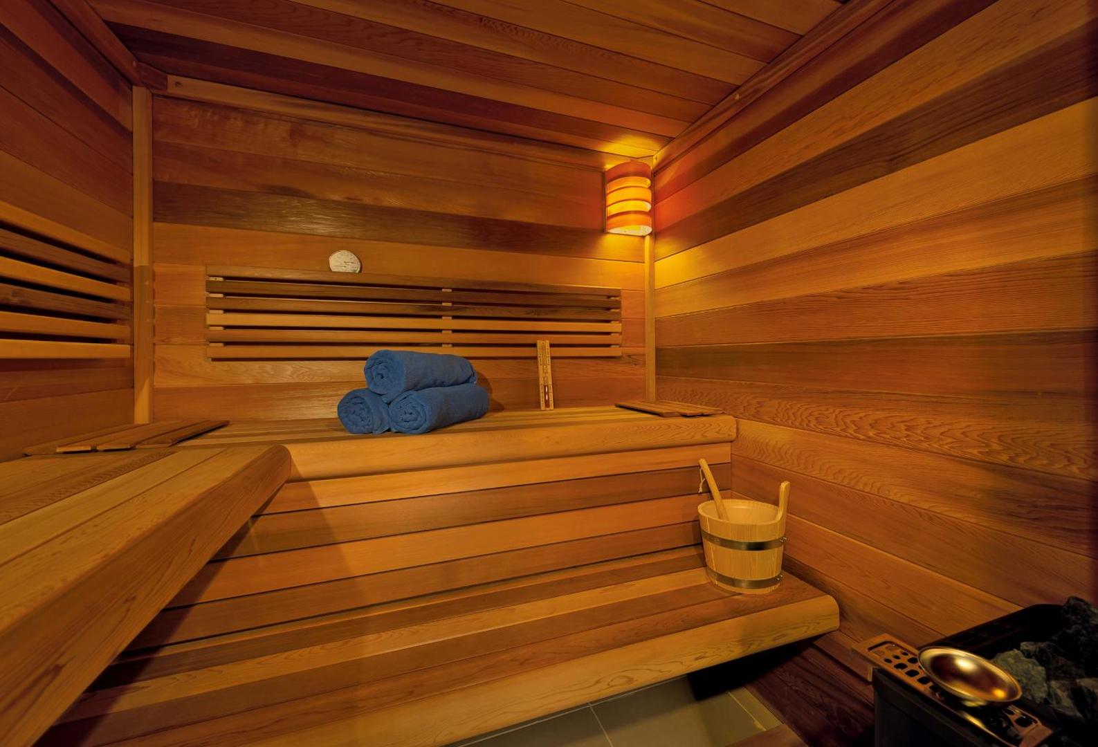 Kriti Beach Hotel spa centra sauna ar koka apdari, ziliem dvieļiem un tradicionālu koka spaini Retimno, Krētā