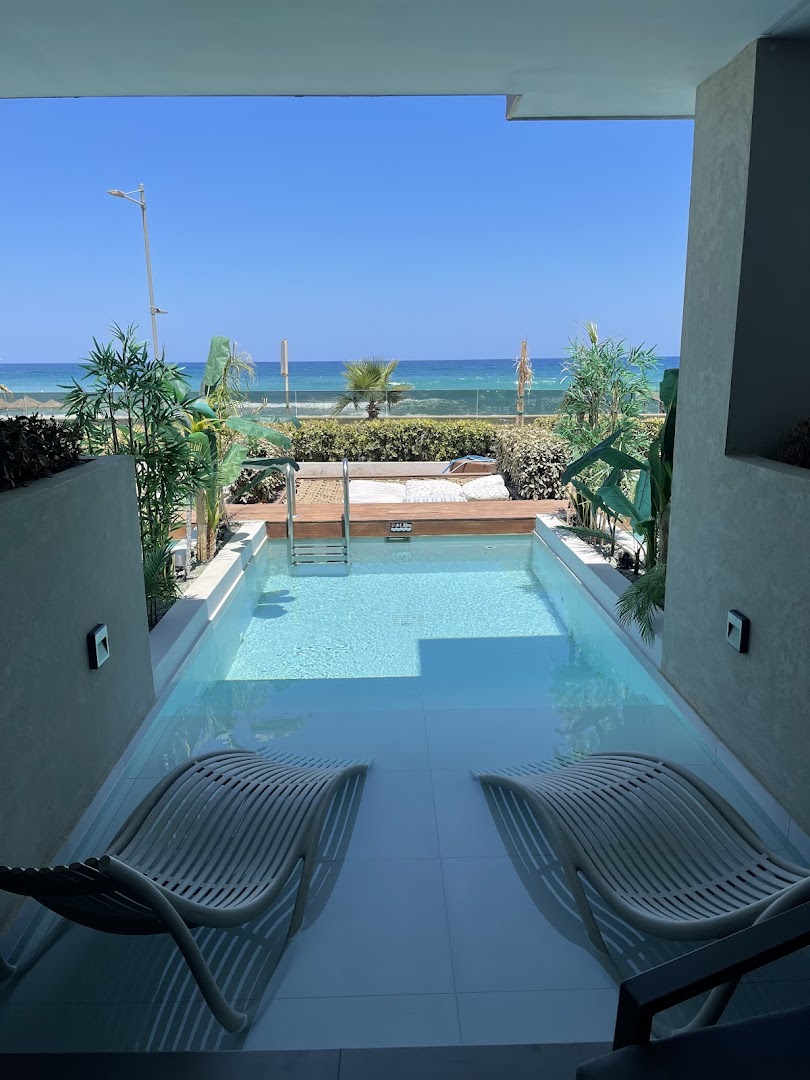 Ikones Seafront Luxury Suites numurs ar tiešu piekļuvi baseinam un skatu uz Vidusjūru Krētas salā — sauļošanās krēsli ūdenī