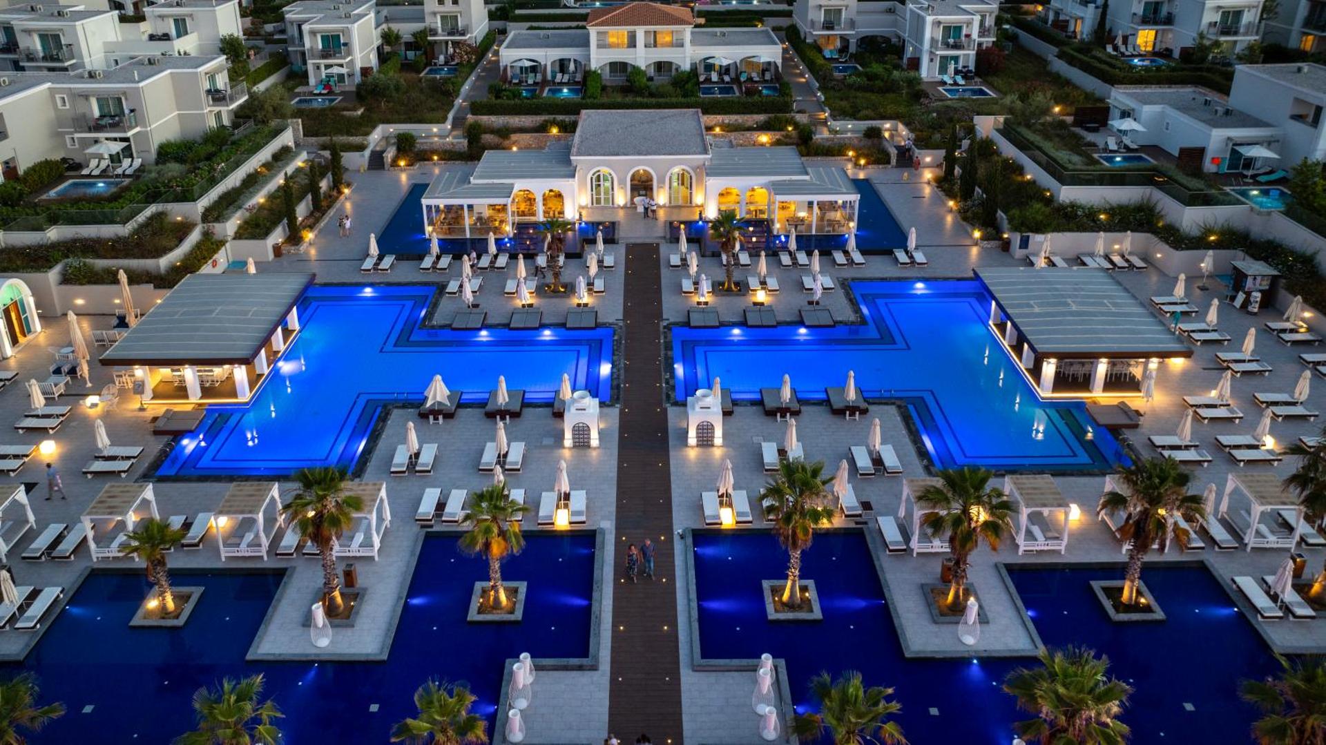 Anemos Luxury Grand Resort vakara skats no augšas uz izgaismotiem baseiniem, centrālo ēku un apkārtējiem numuriem Georgiupoli, Krētā