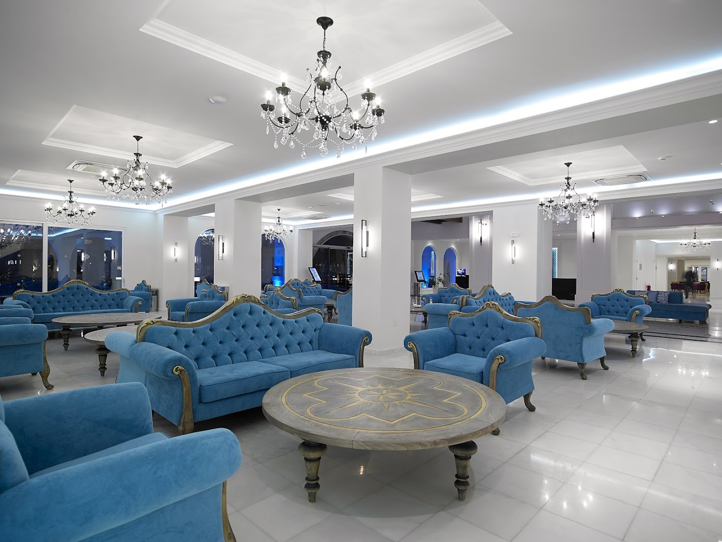 Anemos Luxury Grand Resort plašā lobby atpūtas zona ar grezniem tirkīza dīvāniem, kristāla lustrām un marmora grīdu Krētā