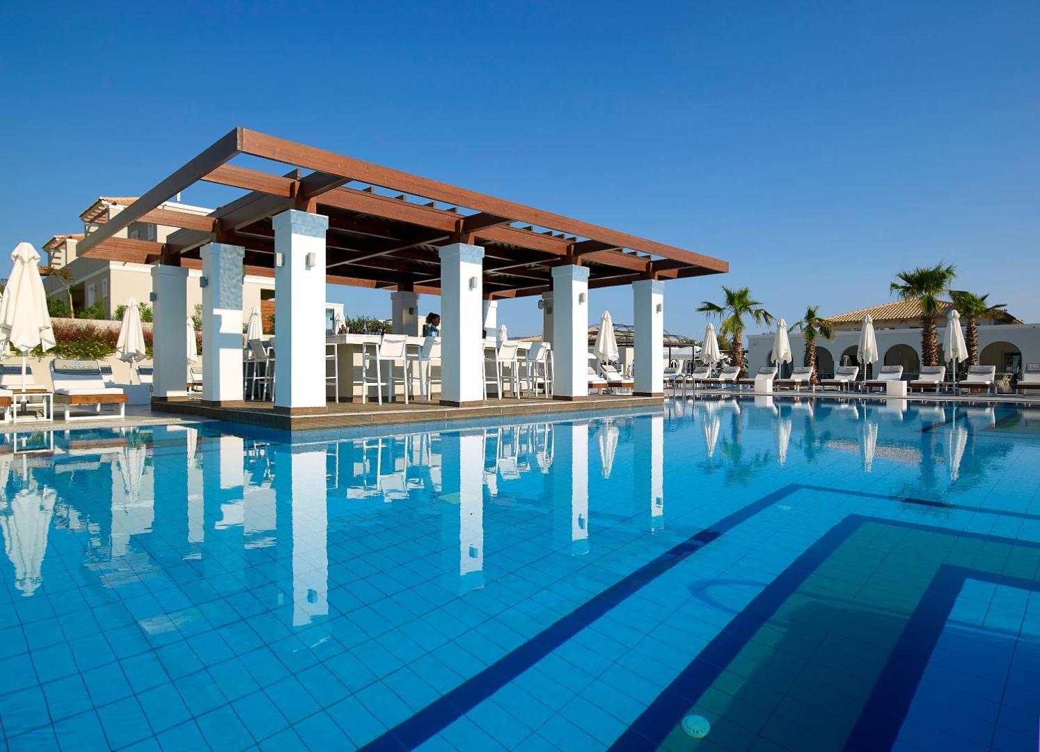 Anemos Luxury Grand Resort āra baseins ar modernu bāru zem koka nojumes un saulessargiem Georgiupoli reģionā