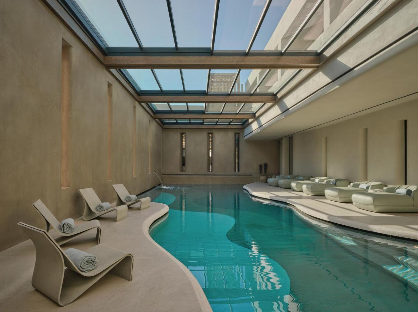 Minos Palace Resort iekštelpu spa baseins ar stikla jumtu, moderniem atpūtas krēsliem un dabisko apgaismojumu