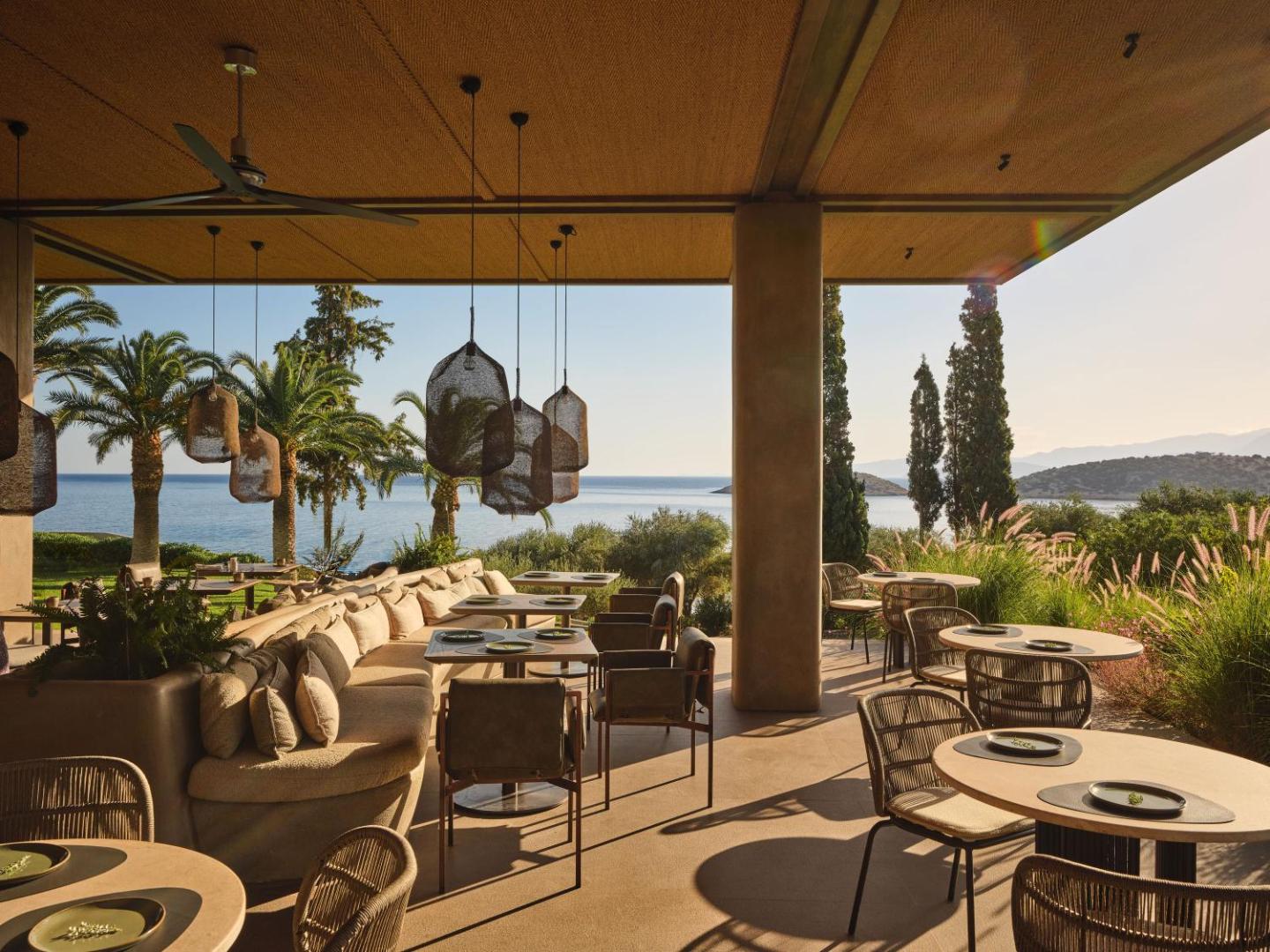 Minos Palace Resort restorāns ar dizaina gaismekļiem, mīkstajiem dīvāniem un panorāmas skatu uz Vidusjūru un piekrastes kalniem.