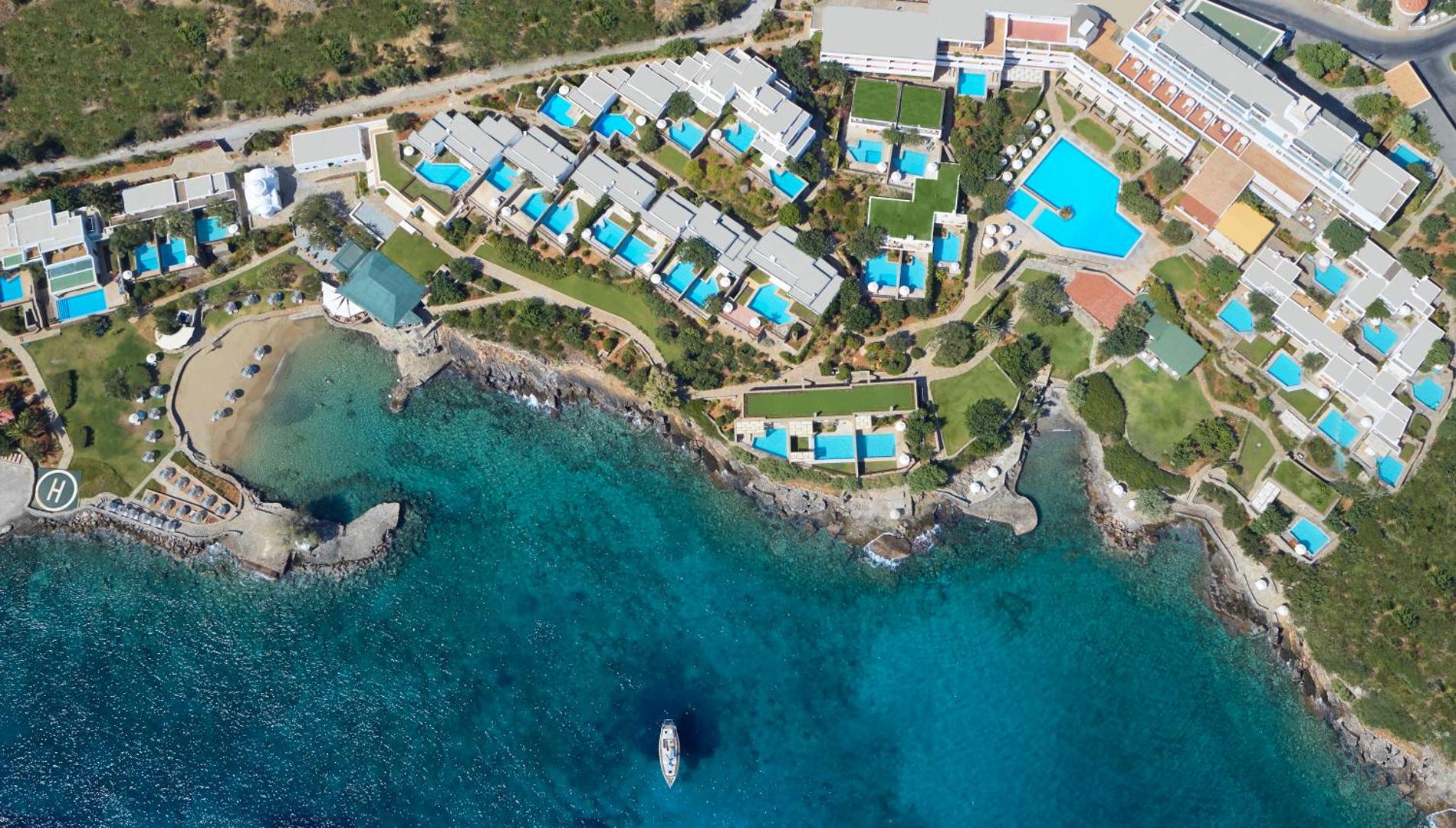Elounda Mare Hotel aerofoto uzņēmums Krētā — liela teritorija ar privātiem baseiniem, galveno baseinu un pieeju tirkīzzilai jūras līcim