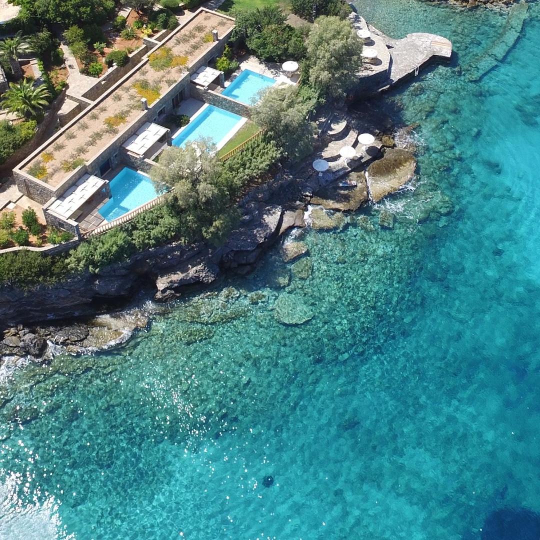 Elounda Mare Hotel numuri ar privātiem baseiniem uz klints malas virs kristāldzidra jūras ūdens Krētas piekrastē