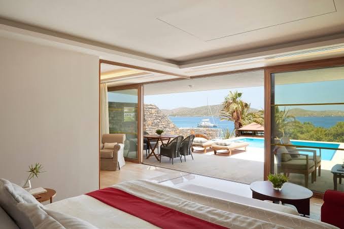 Elounda Mare Hotel luksusa numurs ar plašu terasi, privātu baseinu un skatu uz Mirabello līci Krētā, Grieķijā
