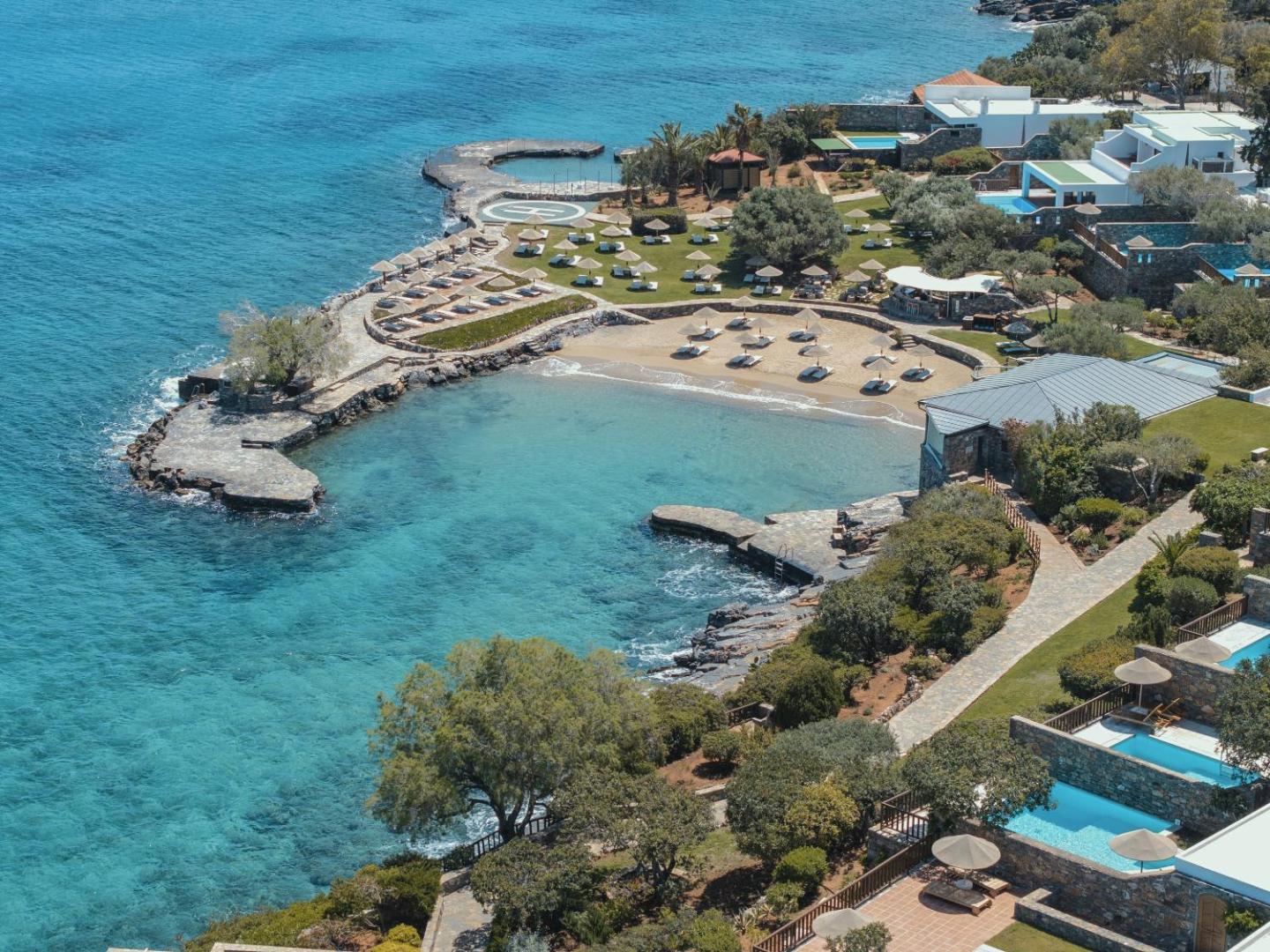Elounda Mare Hotel teritorijas skats no augšas — privātā pludmale, baseini pie numuriem un tirkīzzils jūras ūdens Krētā