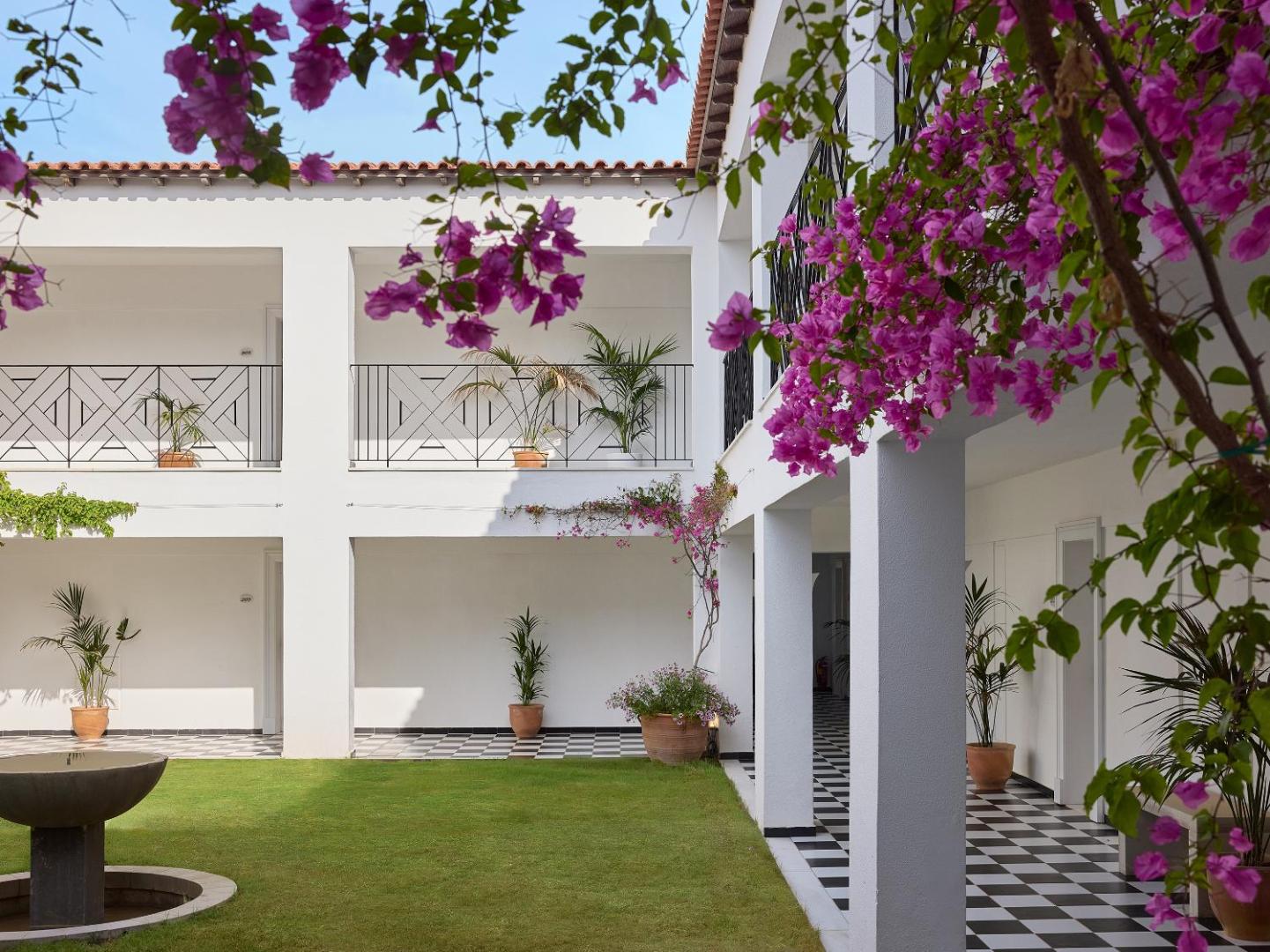 Viesnīcas numuru balkoni un iekšpagalms ar šaha raksta grīdu un ziedošām bugenvillijām Caramel Grecotel Resort viesnīcā Krētā
