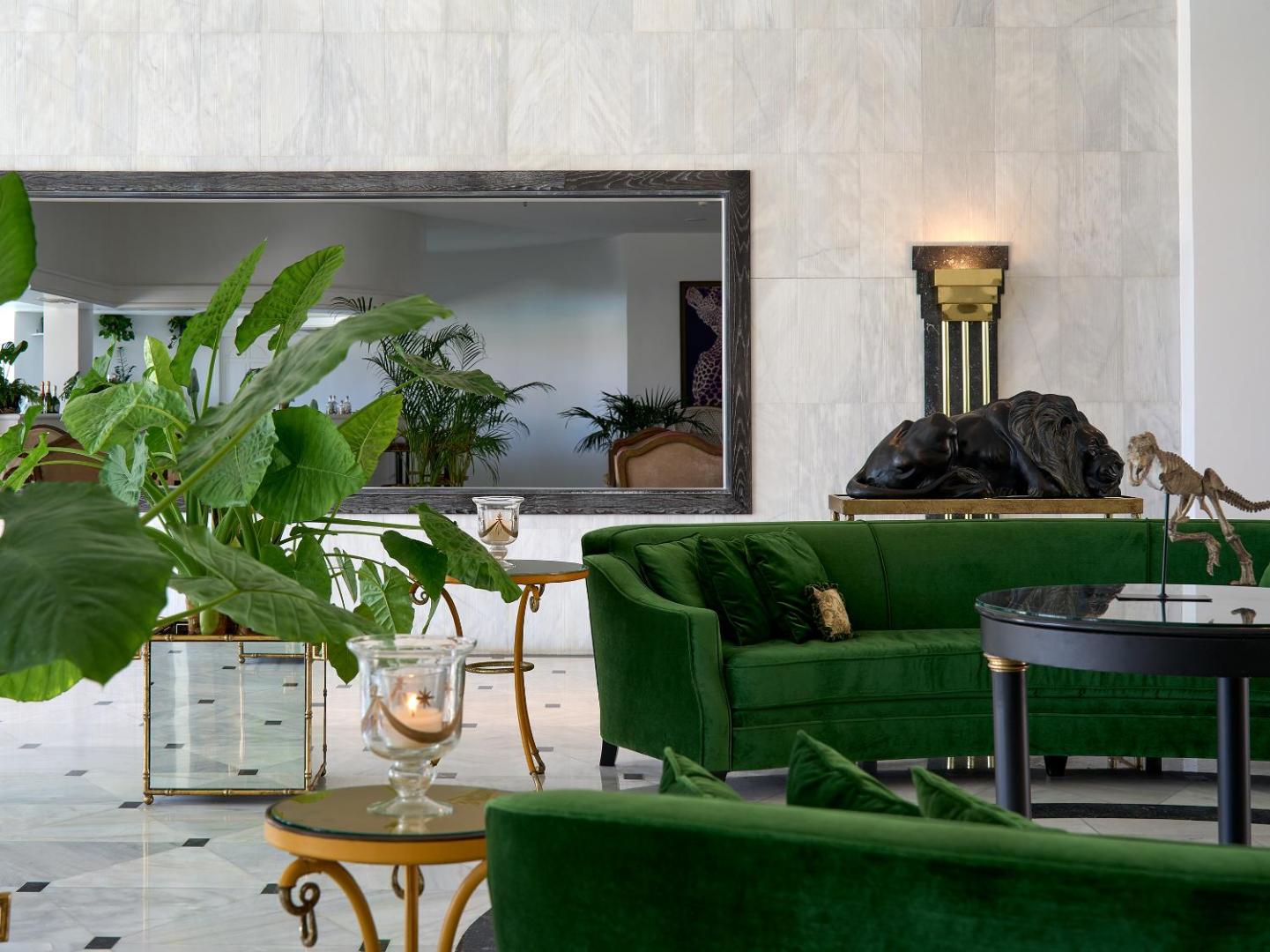 Caramel, Grecotel Boutique Resort interjera detaļas ar zaļu samta dīvānu, zelta galdiņiem un mākslas elementiem viesnīcas atpūtas zonā