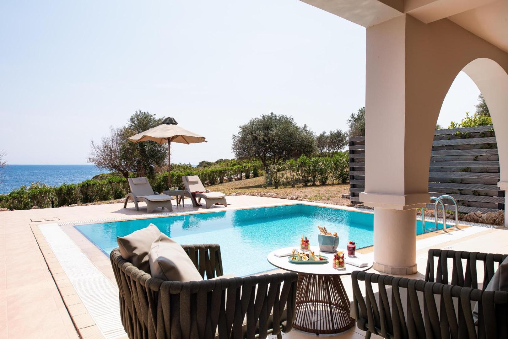 Kresten Royal Euphoria Resort numurs ar tiešu piekļuvi baseinam Rodā — privāta terase ar atpūtas krēsliem un skatu uz jūru