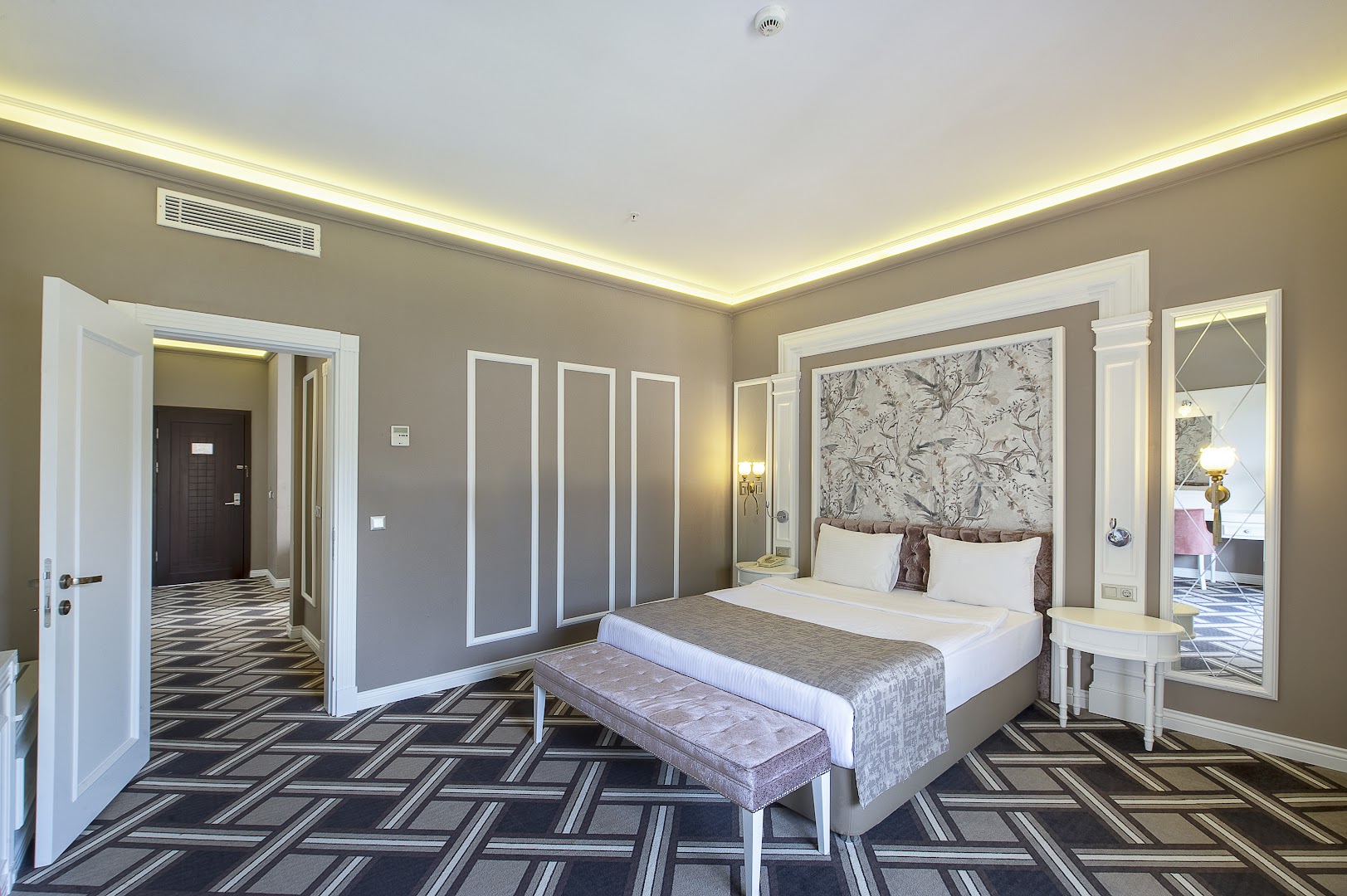 Utopia Resort & Residence elegants divvietīgs numurs ar rakstainu paklāju, dekoratīvu sienas paneli virs gultas un spoguli Alānijas reģionā