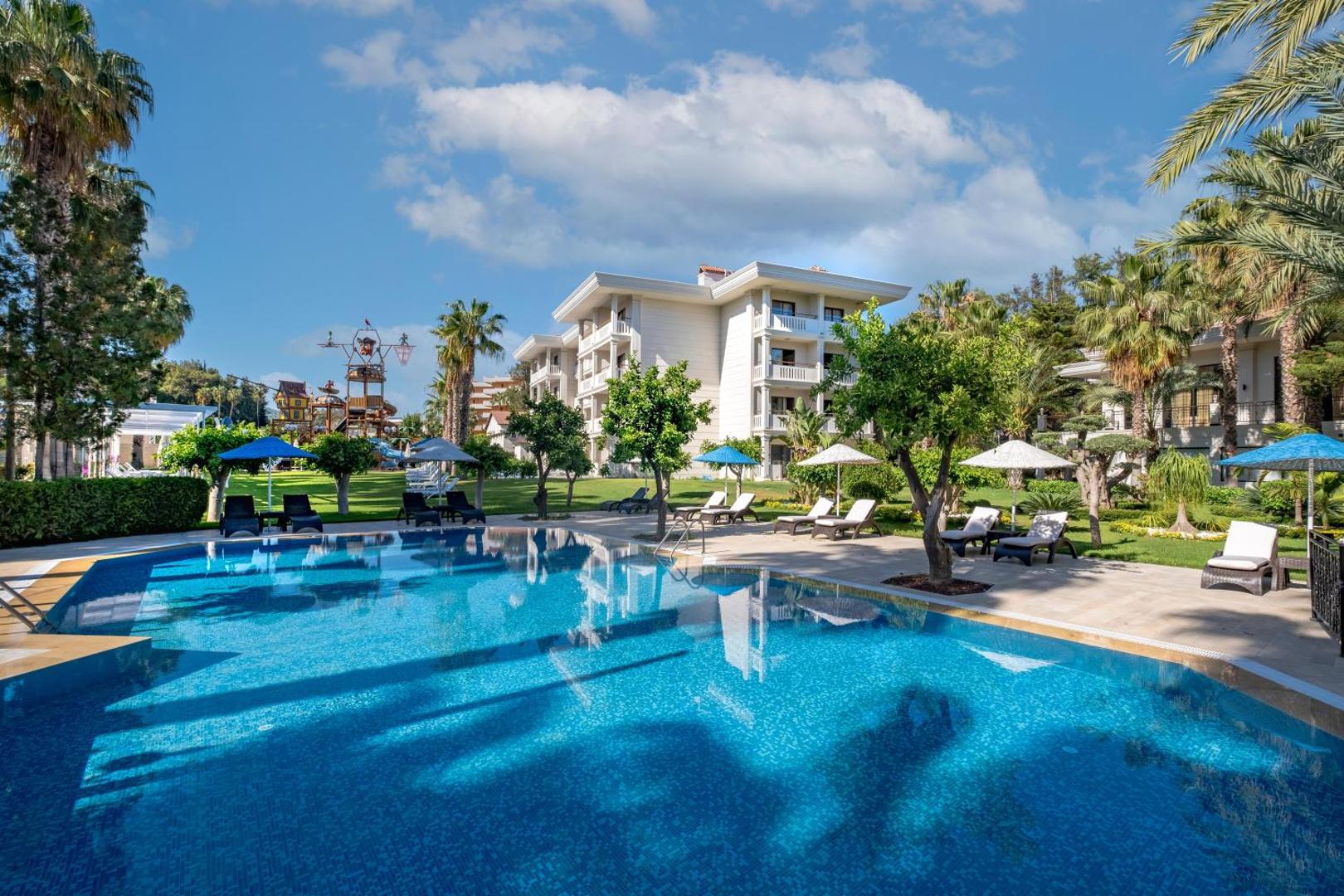 Utopia Resort & Residence āra baseins ar skatu uz dārzu un bērnu atrakciju parku fonā — zālājs un atpūtas zona