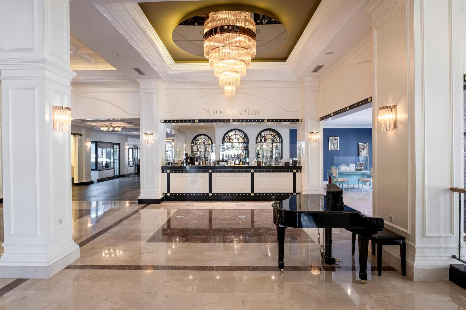 Utopia Resort & Residence Panorama Bar vestibils ar melnu flīģeli, kristāla lustru un klasisku interjeru gaišos toņos Alanjā