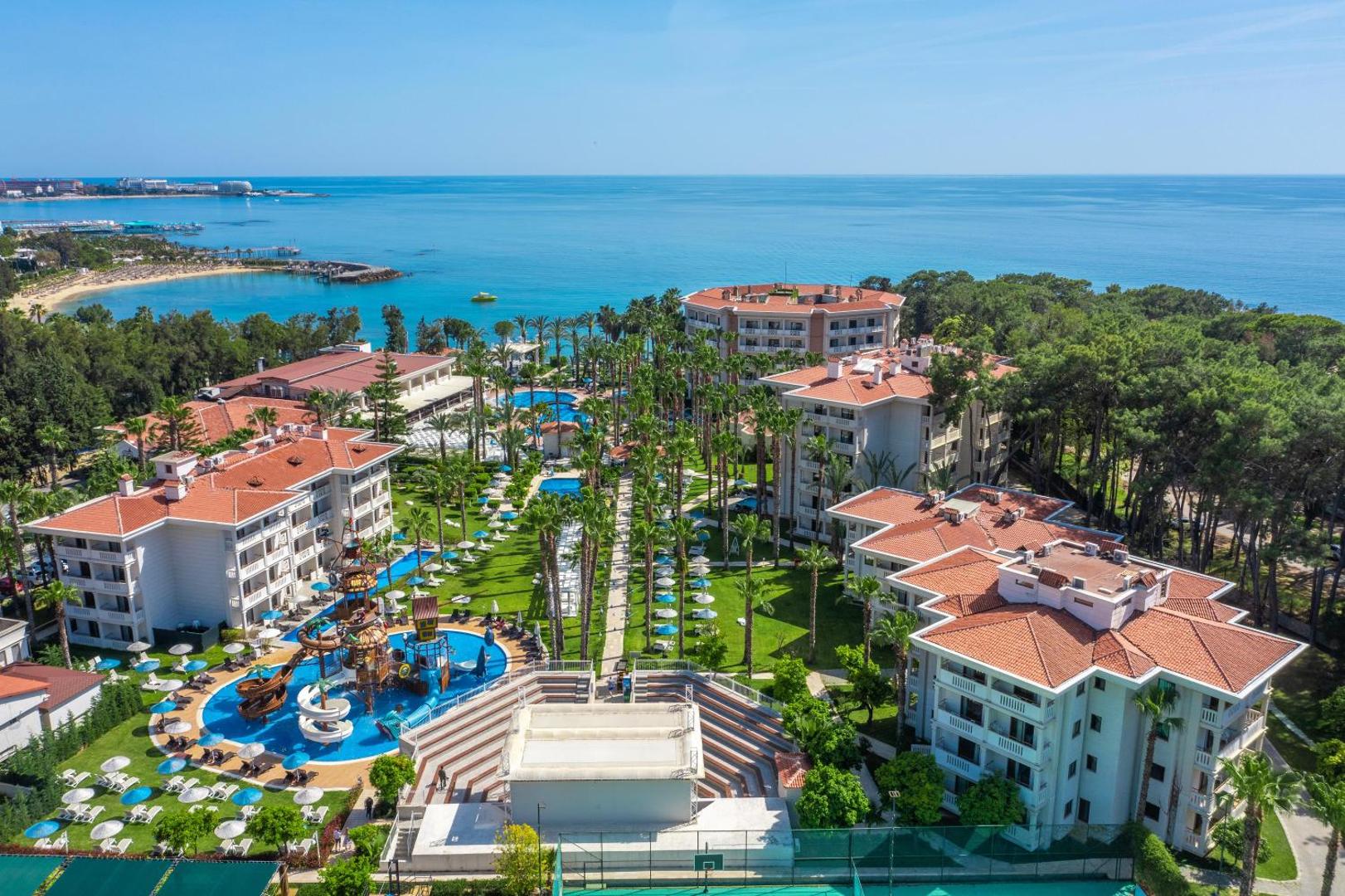 Utopia Resort & Residence bērnu akvaparks ar pirātu kuģi, baseiniem un sauļošanās terasēm, skats no augšas uz kūrorta teritoriju.