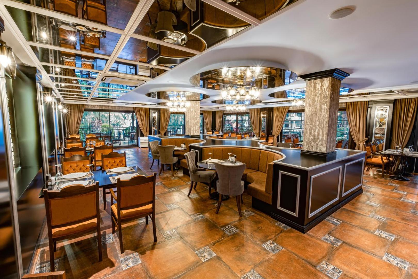 Utopia Resort & Residence galvenais restorāns ar greznu interjeru, spoguļu griestiem un mīkstajām mēbelēm siltos brūnos toņos Alanjas reģionā.